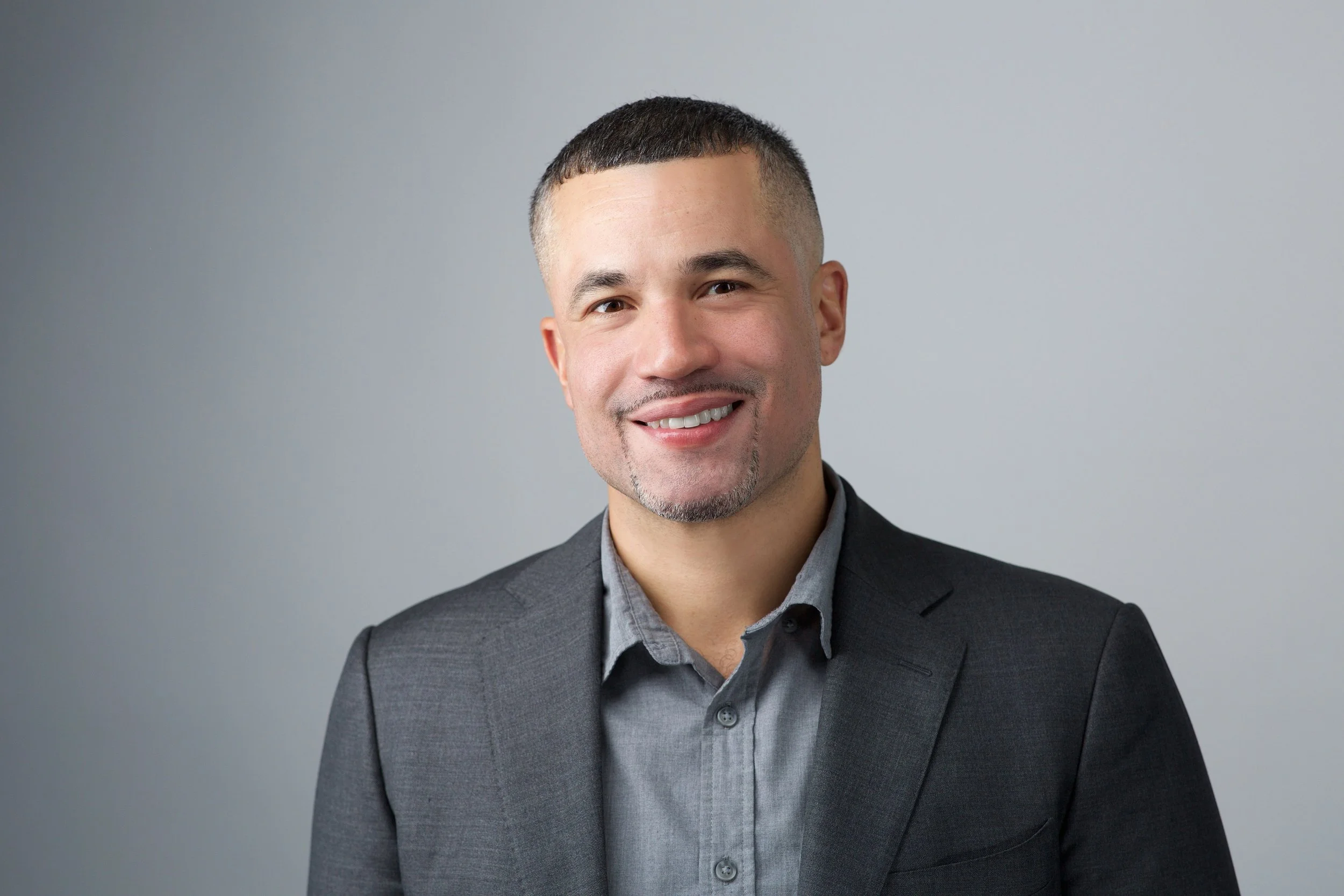 Smiling man in a gray suit on a gray background.