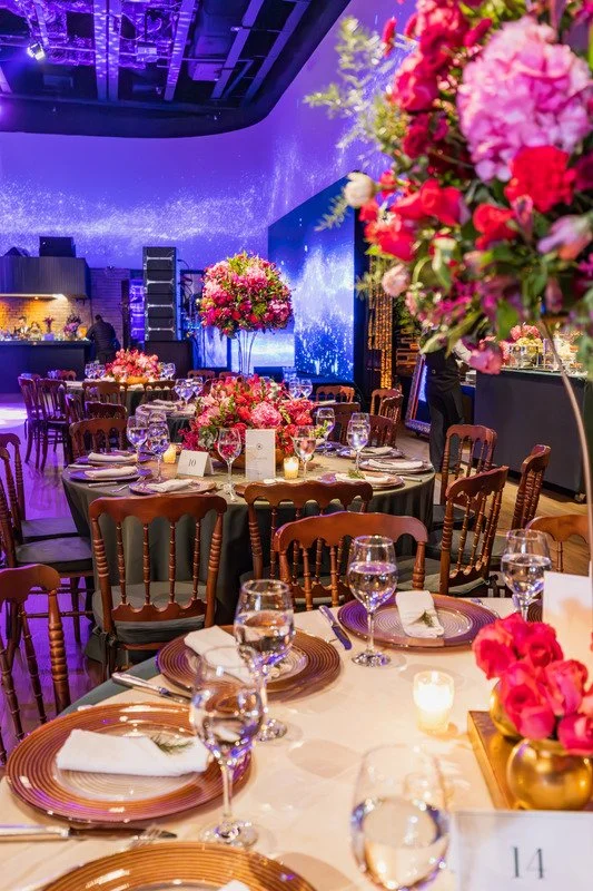 Elegant event venue with round tables, floral centerpieces, and candlelight