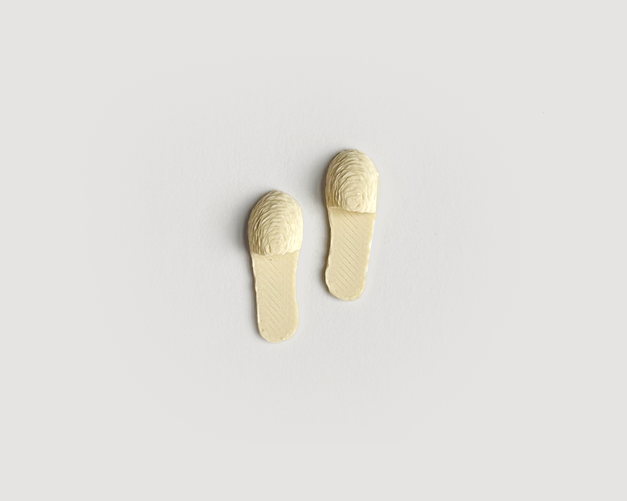 Pair of 1:12 scale miniature ivory slippers with soft texture, designed for dollhouses and cozy fall scenes.
