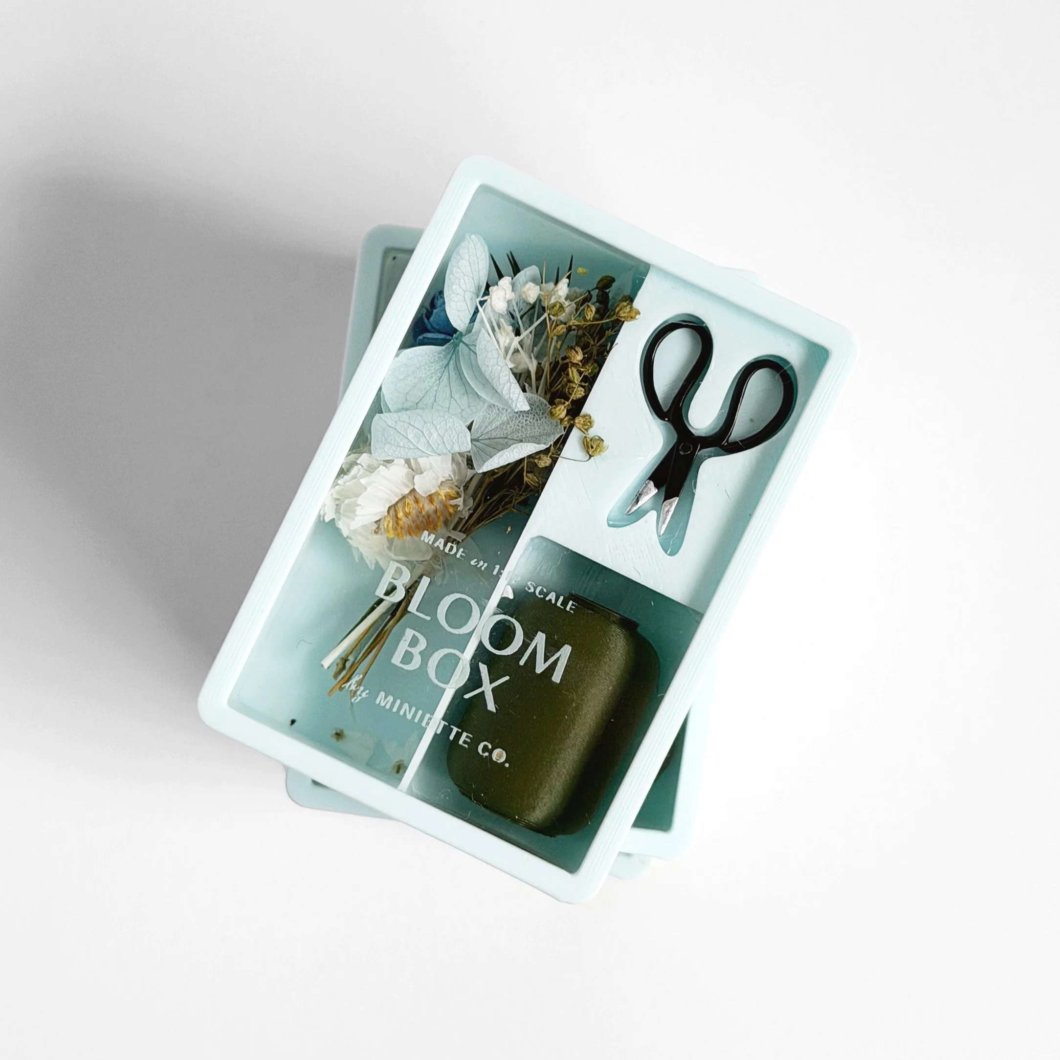 Top view of blue Bloom Box miniature floral arrangement with layered textures and preserved flowers