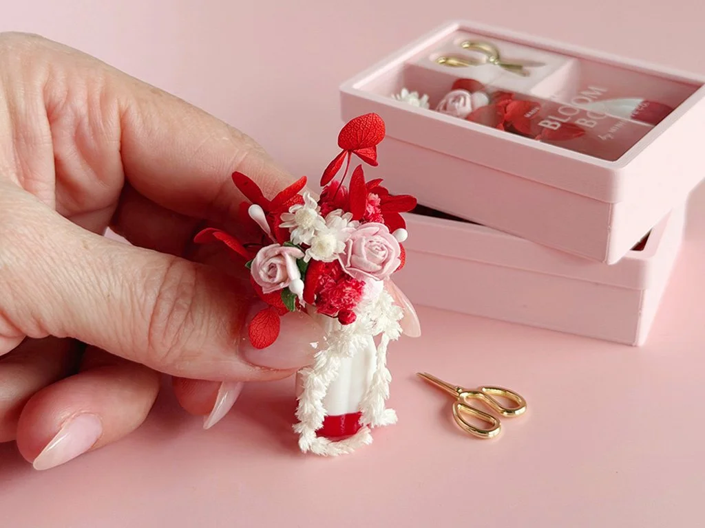 Close-up of miniature Valentine flowers featuring blush roses, red foliage, and white accents