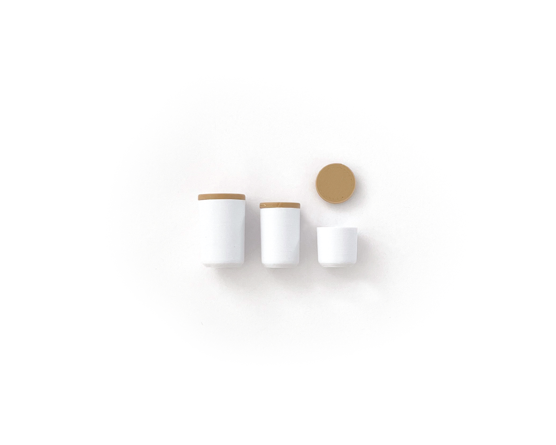 Set of three dollhouse canisters. Varying sizes from large to small in bright white with natural blonde wood lids.