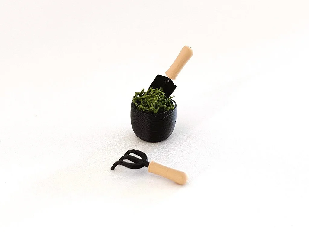 Close-up of faux-wood handles and modern black finish on miniature garden tools.