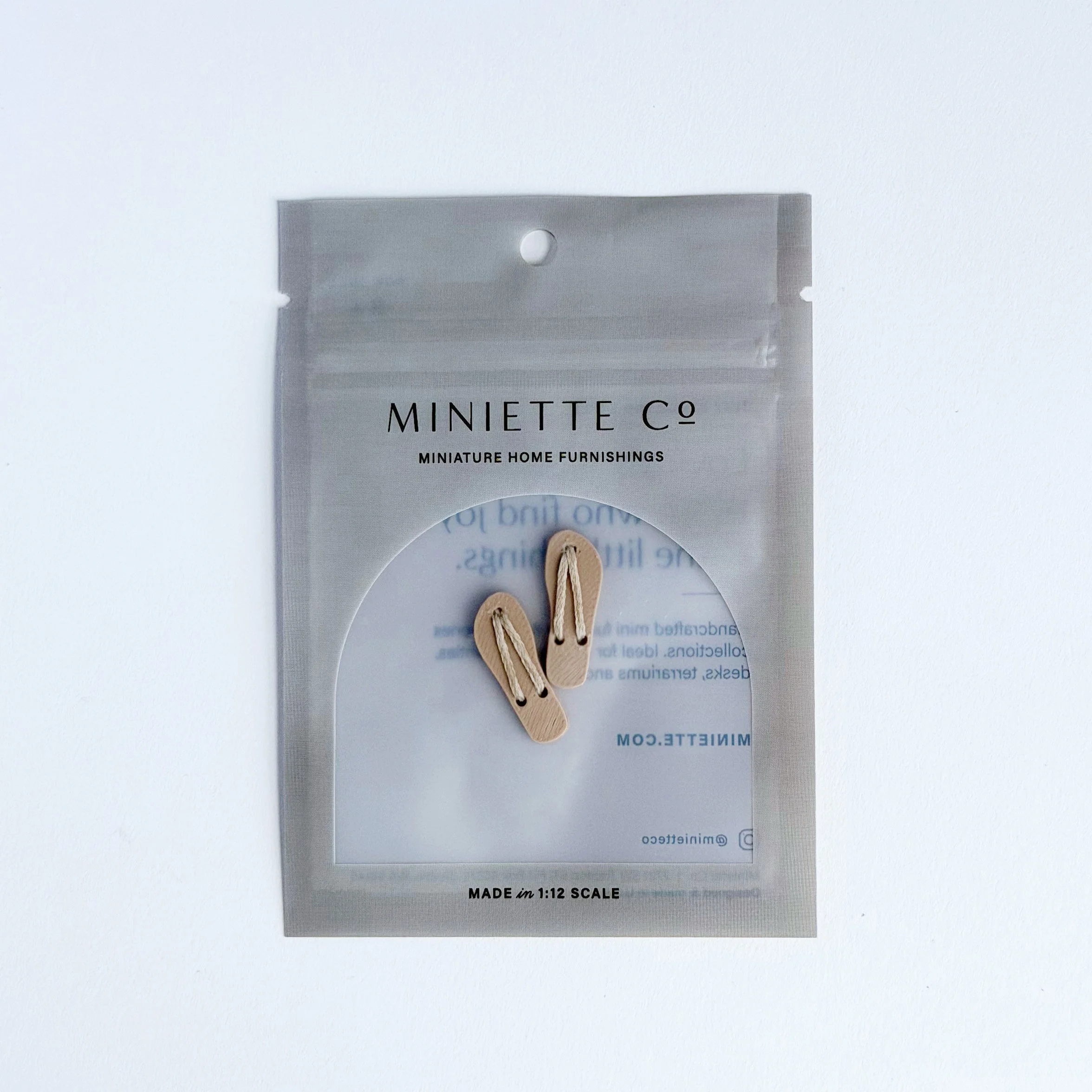 Close-up of tan miniature flip flops with soft, natural tone