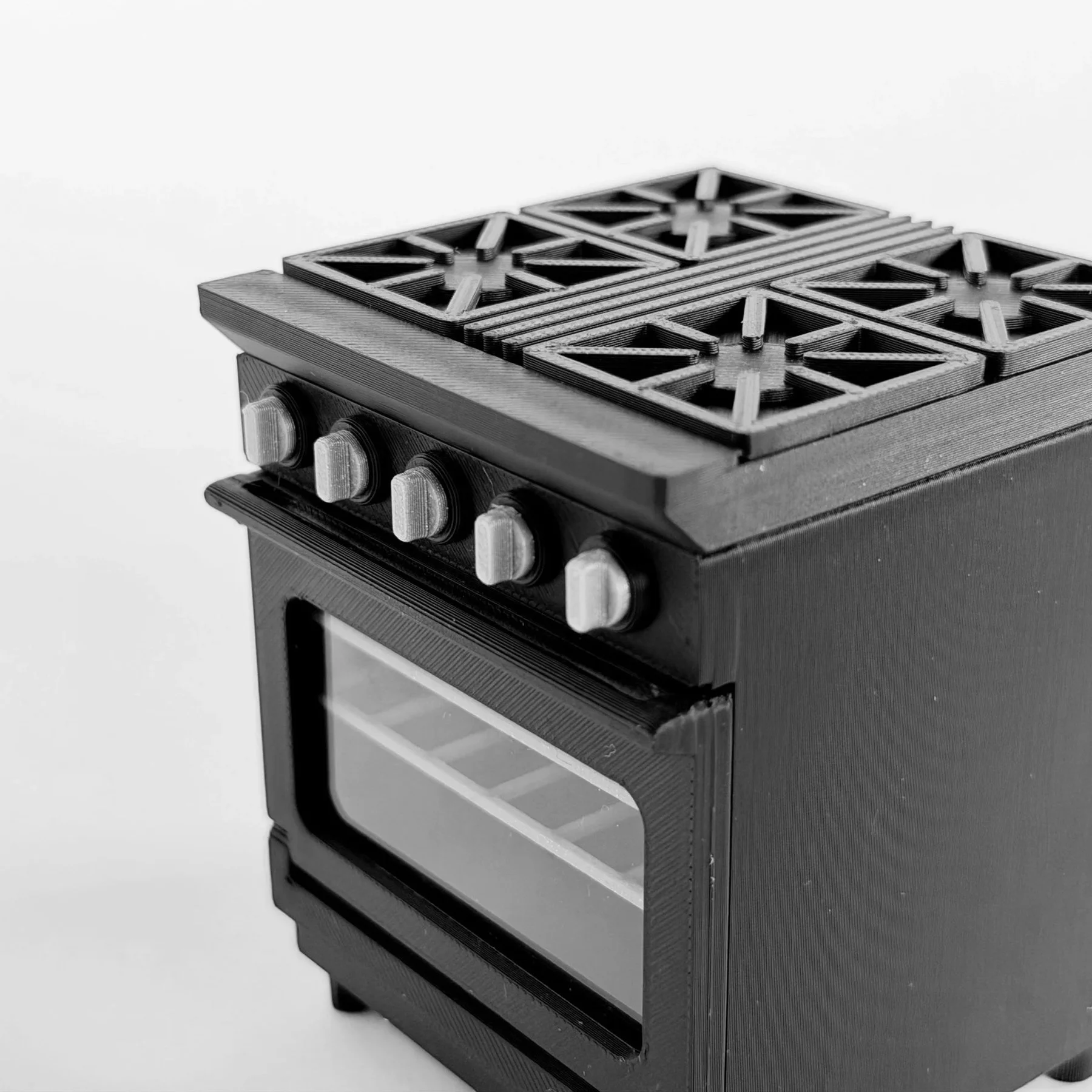 Detail view of silver-tone control knobs on a black 1:12 scale miniature stove and oven.