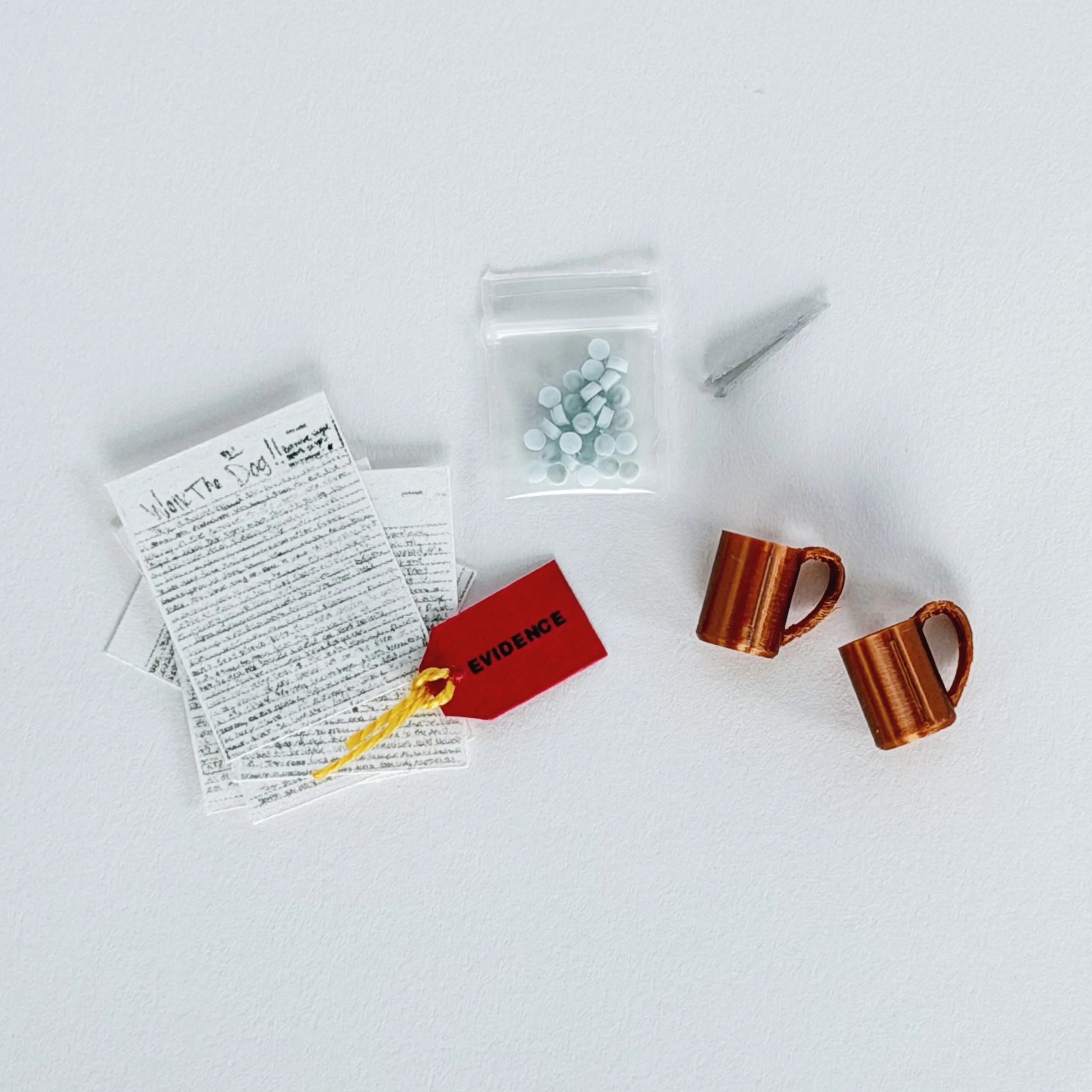 Close up of 1:12 scale miniature evidence box with tiny accessories arranged inside clear acrylic display case