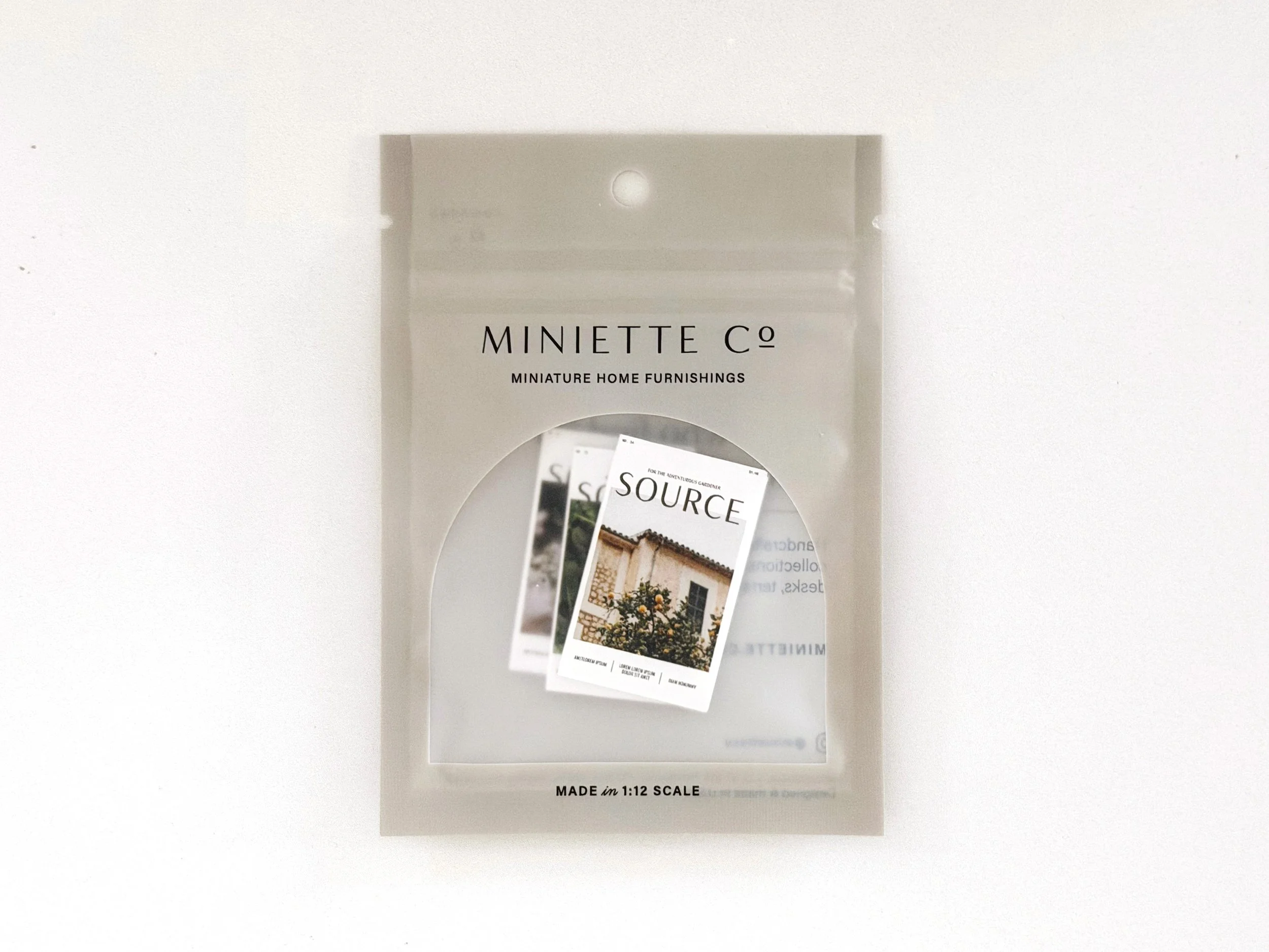 Oversized miniature garden magazines styled as stacked decor for dollhouse interiors.