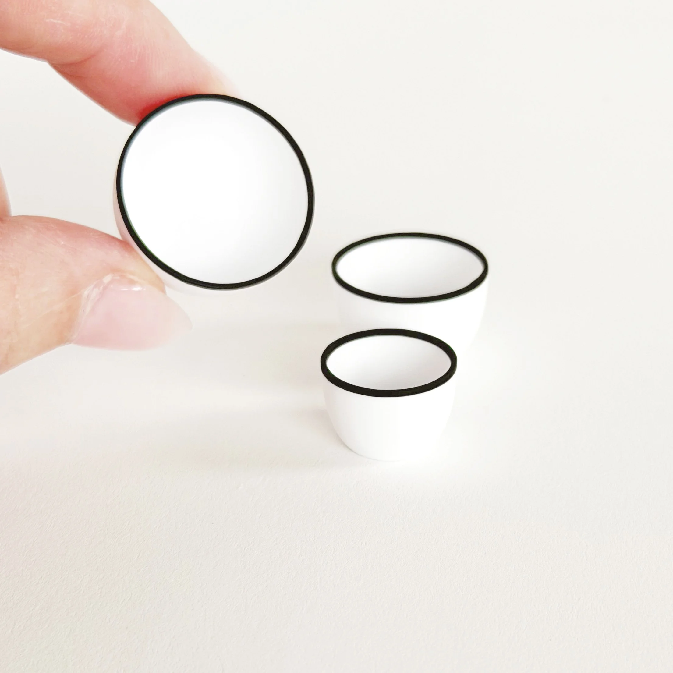 White miniature nesting bowls with black rim shown unstacked, highlighting simple shapes and clean design.