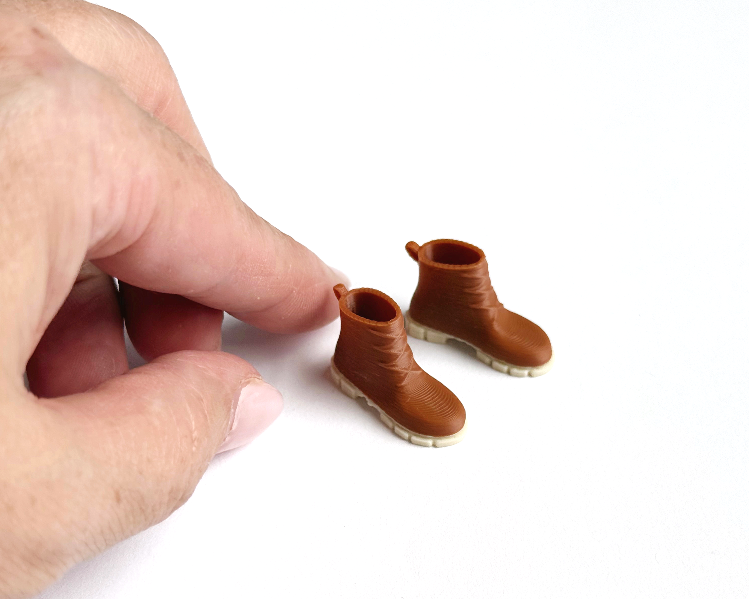 Miniature dollhouse boots, brown plastic shoes in 1:12 scale. Tiny footwear accessory for mudroom, entryway, or bedroom scenes.