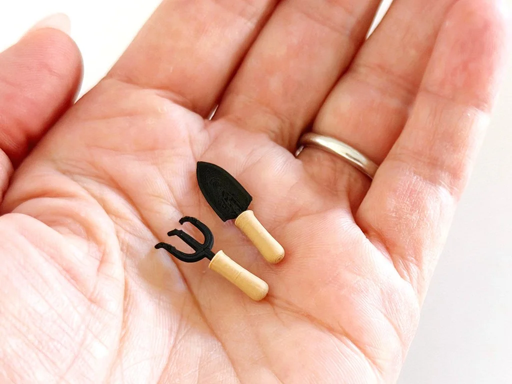 Handheld size reference showing scale and proportions of the miniature spade and cultivator.