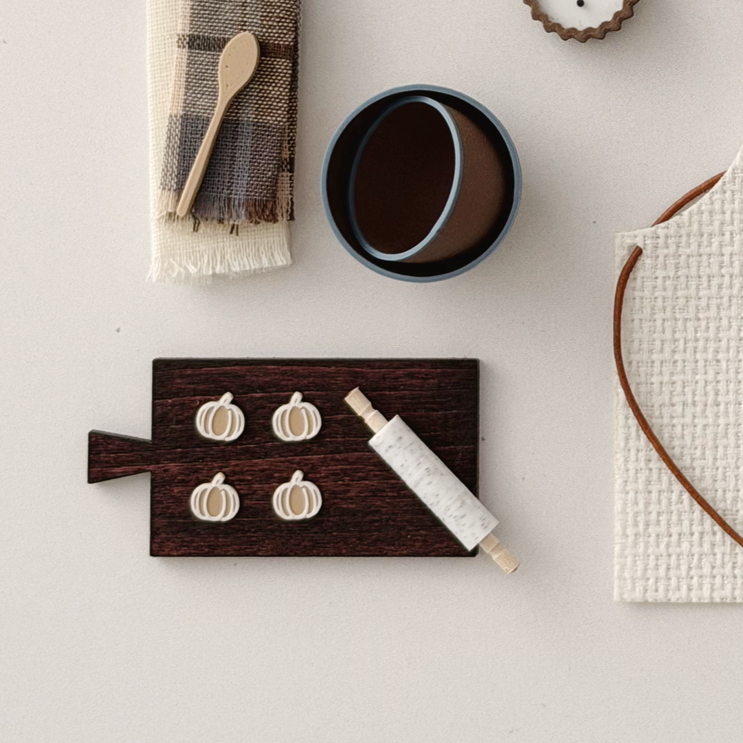 Miniature pumpkin cookies arranged on a dark wood cutting board for fall