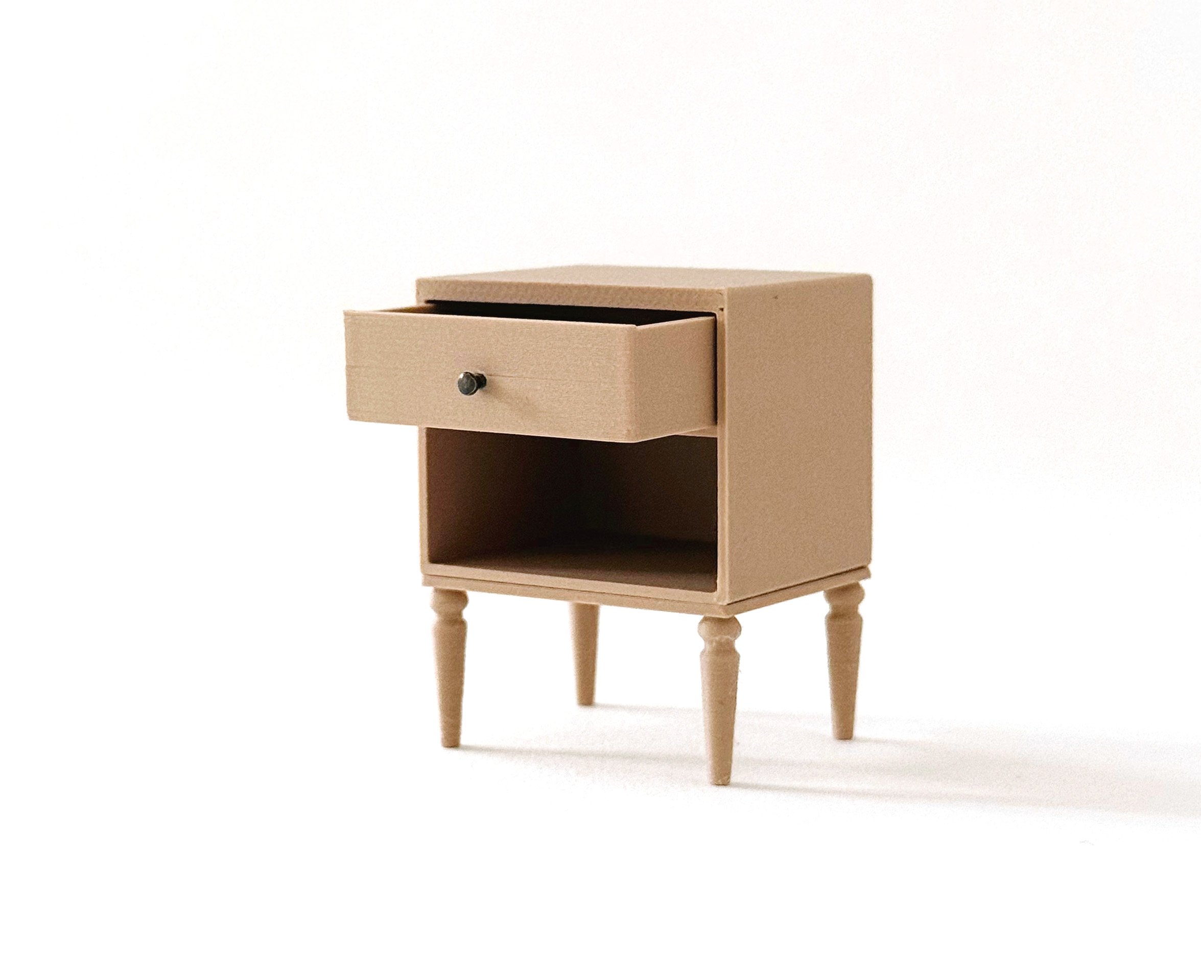 Miniature dollhouse nightstand with opening drawer in natural wood color. Elegant, modern storage featuring intricate tapered legs.