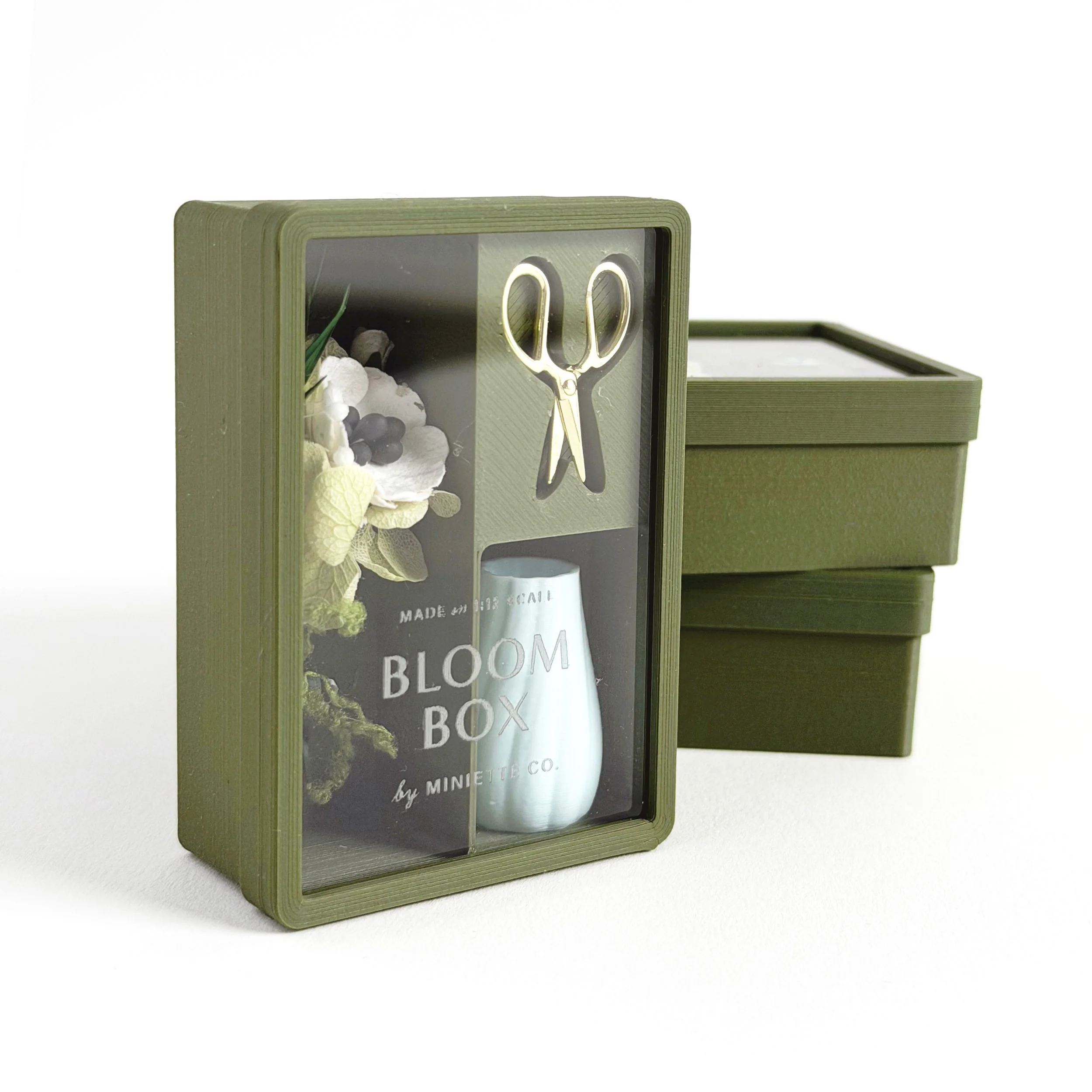 Green floral Bloom Box miniature gift set styled in clear box with preserved flowers, vase, and scissors