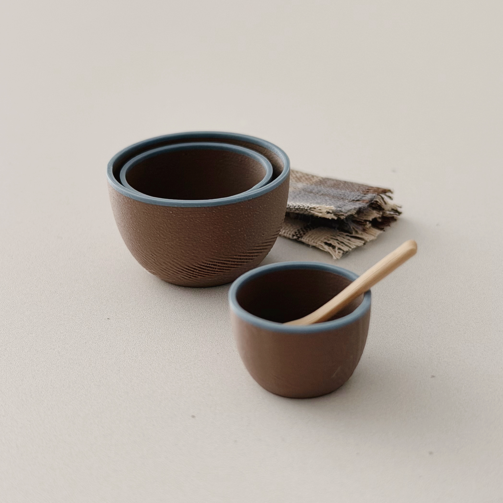Three brown 1:12 scale miniature nesting bowls with soft blue rims