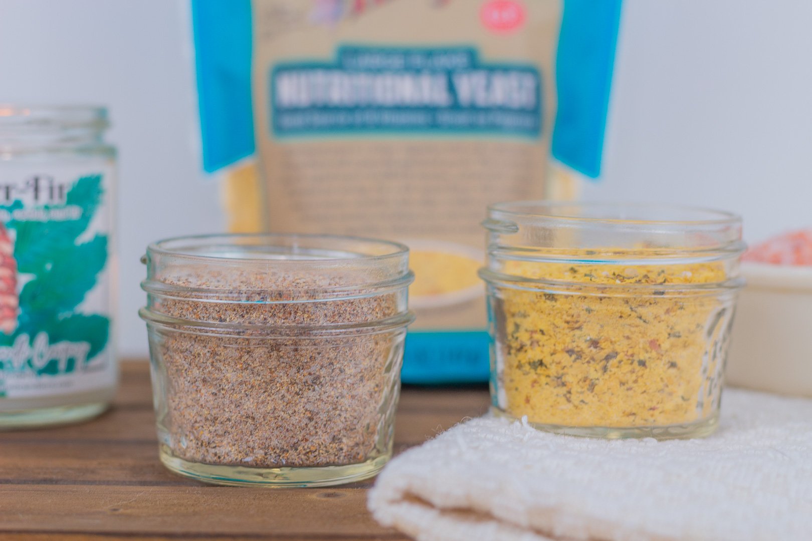 Two glass mason jars filled with homemade yellow chicken bouillon powder and reddish seasoned salt.