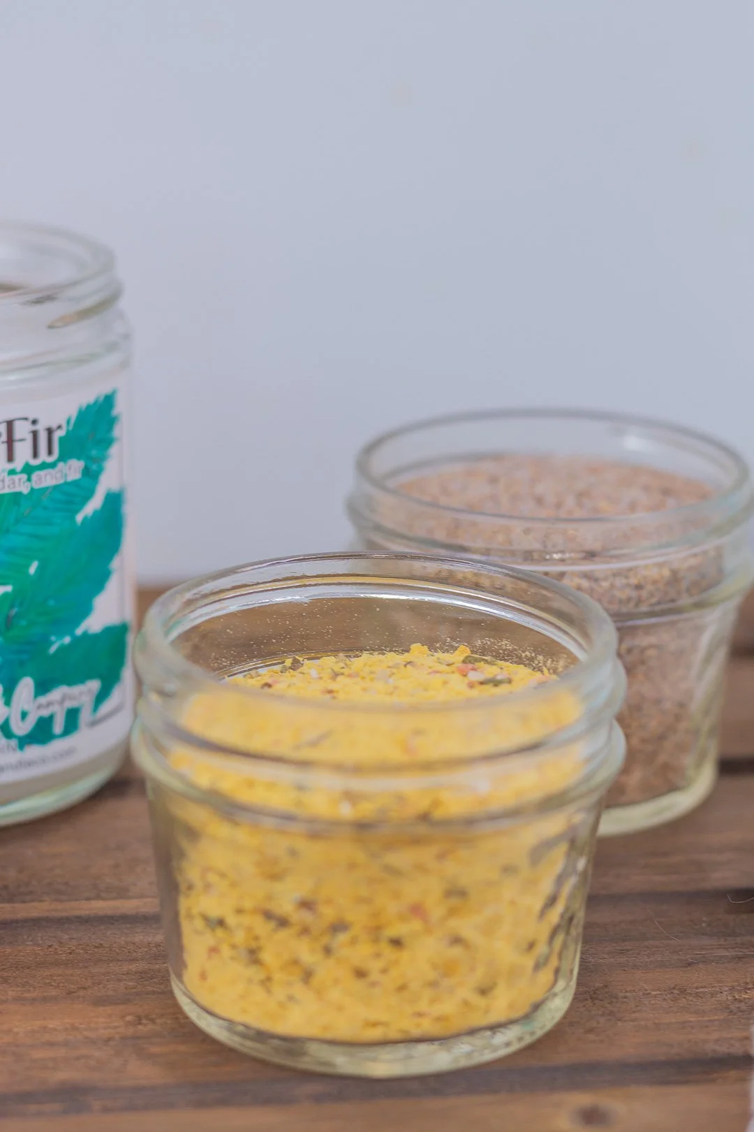 Homemade chicken bouillon in glass jar with seasoned salt in background.