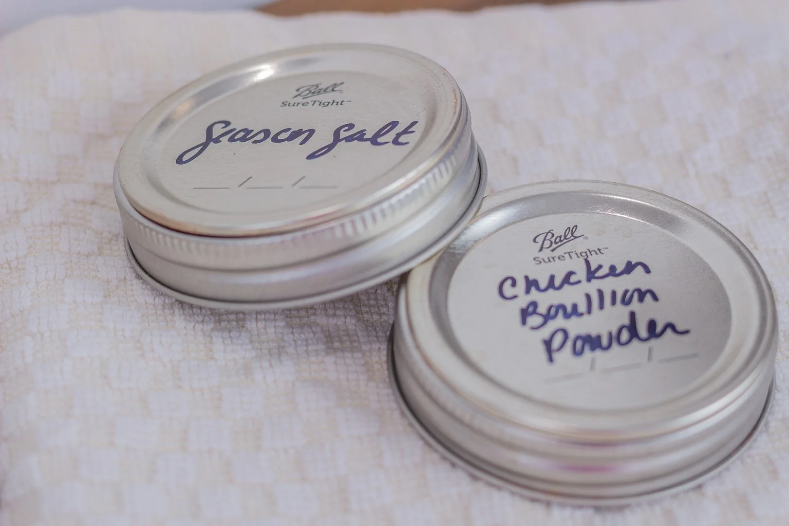 Lids with handwritten labels indicating they are for "Seasoned Salt," or "Chicken Bouillon Powder."