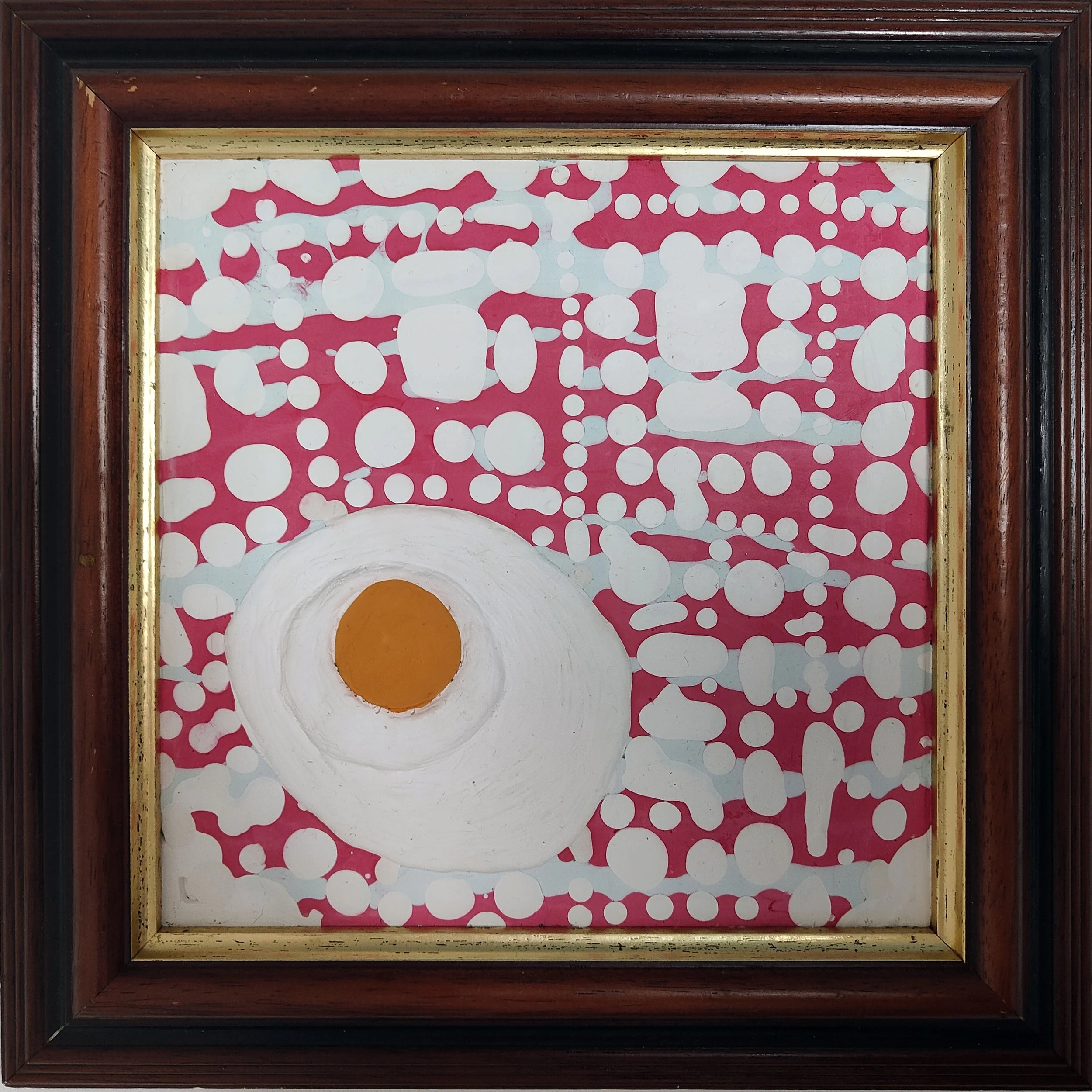Close-up of a framed abstract artwork with pink, white, and orange colors and circular patterns.