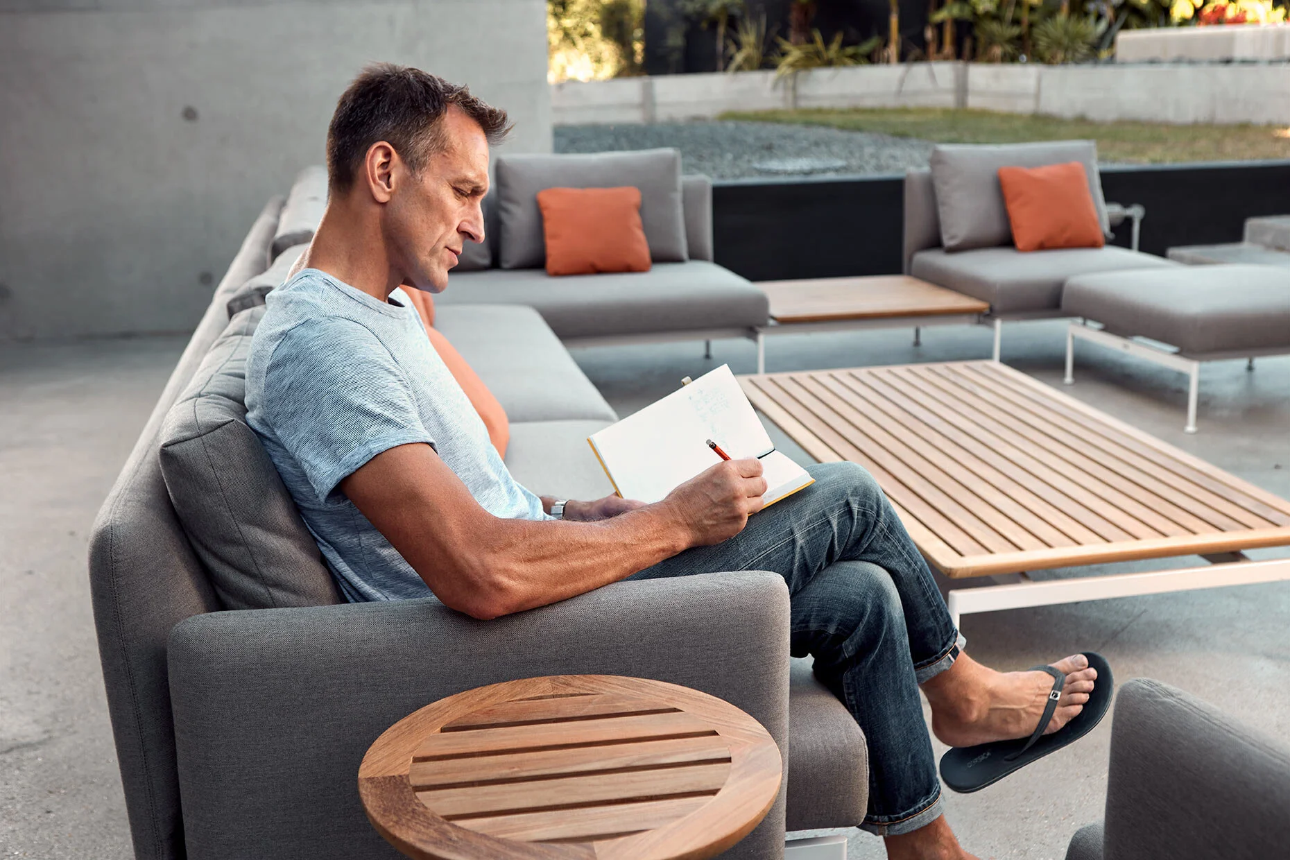 Man writing in notebook on outdoor couch