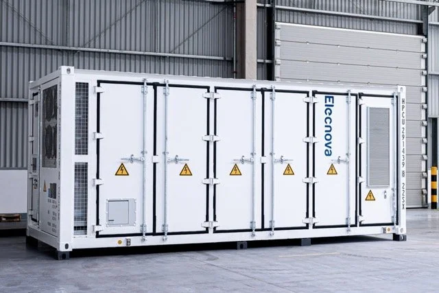 En stor, hvit isolert konteinerenhet med dørlås i en industribygg, merket Elconova.
