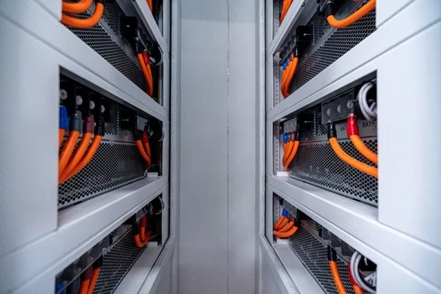 Innside av et datasenter eller elektrisk rom med rackservere og store orange kabler.