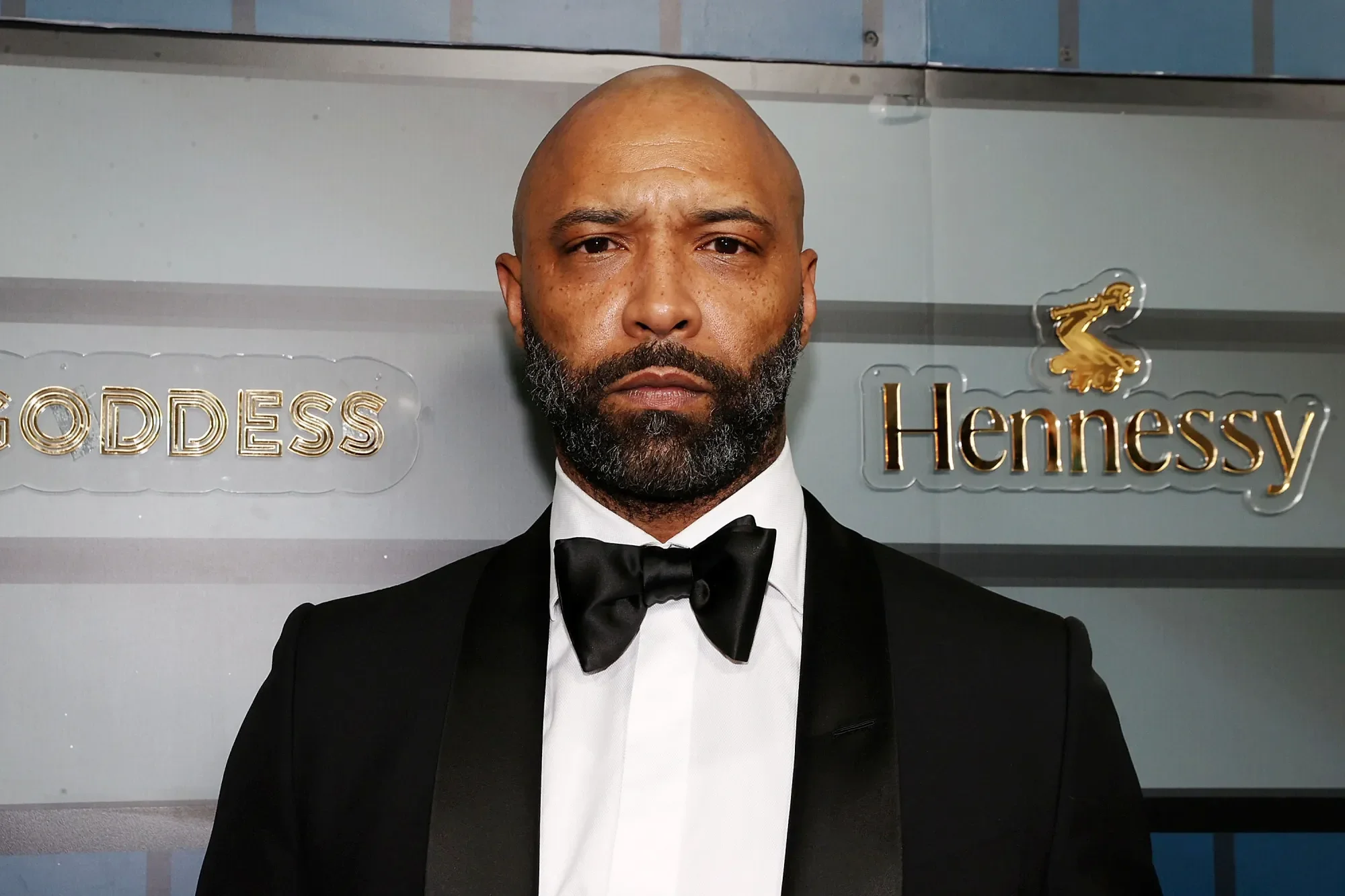 Portrait of Joe Budden wearing a black tuxedo and bowtie at a formal event.