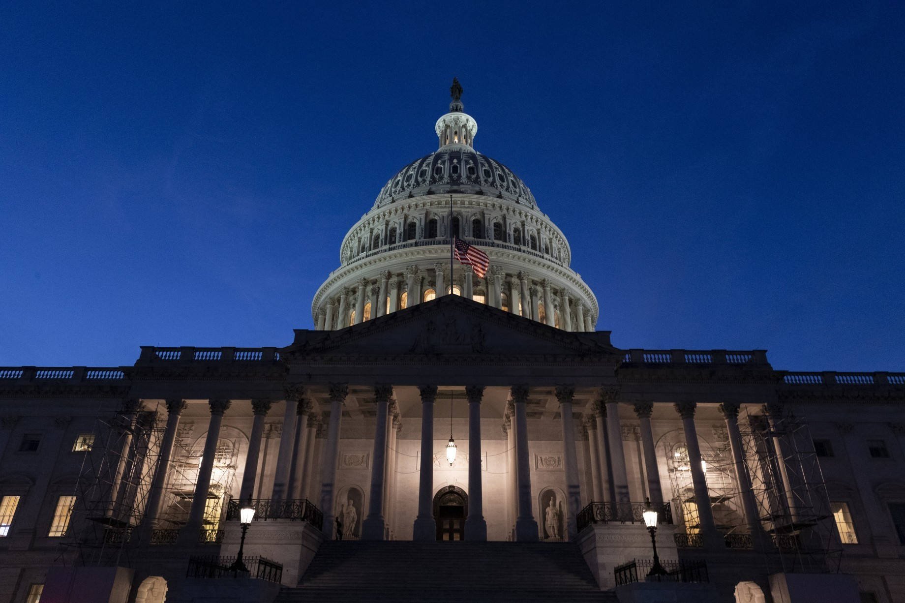The United States Capitol building brightly lit at night against a dark blue sky.