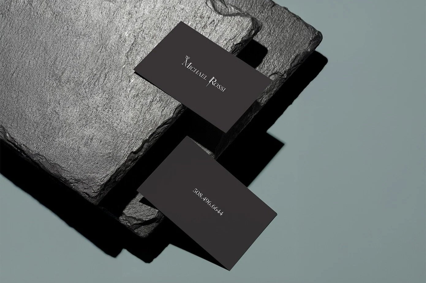 A redesigned business card for hairstylist Michael Rossi, showcasing his unique style and expertise in hair artistry. The card features a sleek layout highlighting his name and profession prominently, along with contact information.