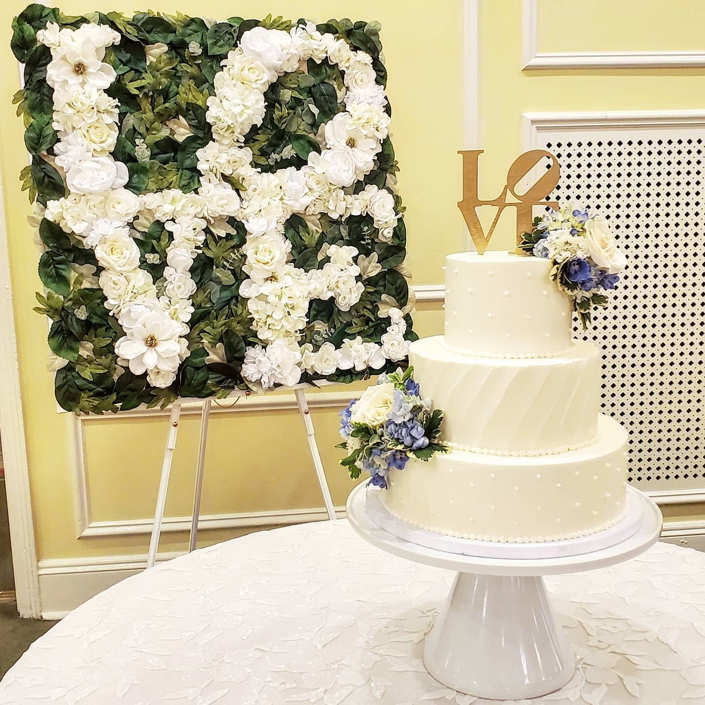 I am in love with this floral and greenery backdrop matching this topper 😍 As always, every cake looks stunning at @thecarolinainn #carolinainn #wedding #weddingcake #weddingcakes #cake #cakes #allwhitecake #allwhitecakes #buttercreamcakes #buttercr