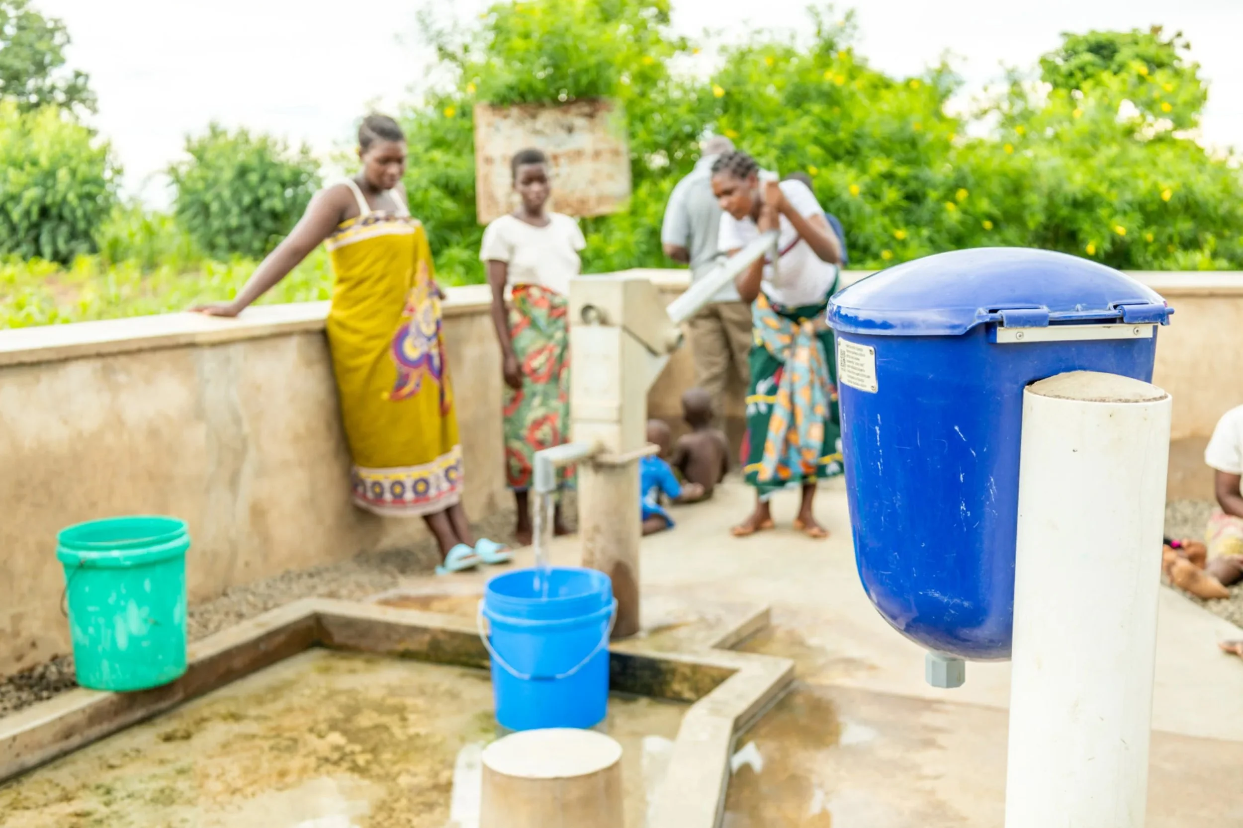 People gathered around Evidence Action chlorine dispenser.jpeg