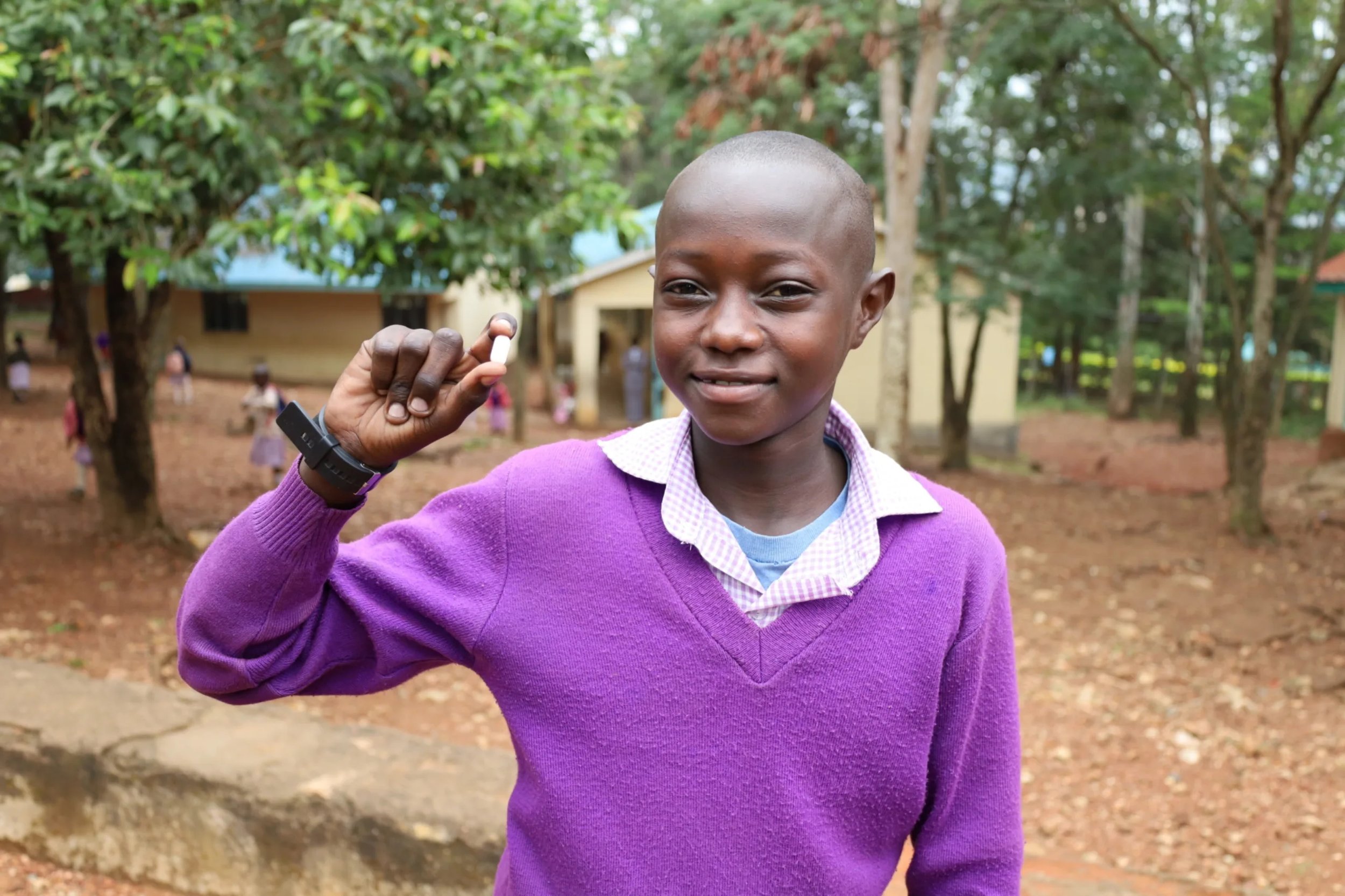 Child holds up a deworming tablet