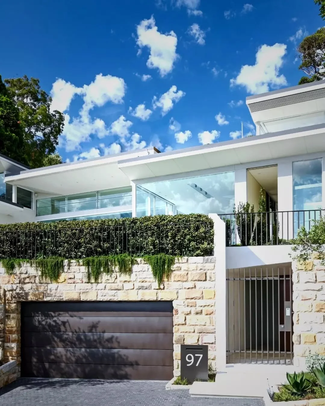 A layered street presence defines the arrival to this contemporary home.

The solid sandstone base anchors the building to the site, housing the garage and entry below, while the upper level contrasts with a lighter expression. Clean white forms exte