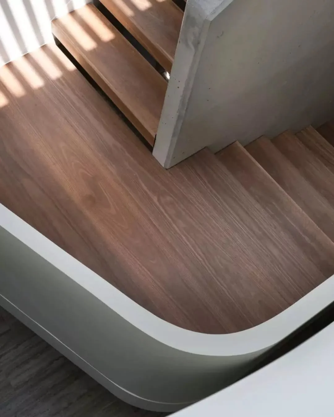 Viewed from above, the stair is read in relation to the surrounding upper level, where the space wraps around the opening and guides movement between areas. Light moves across the balustrade, emphasising its profile and the depth of the space, reinfo