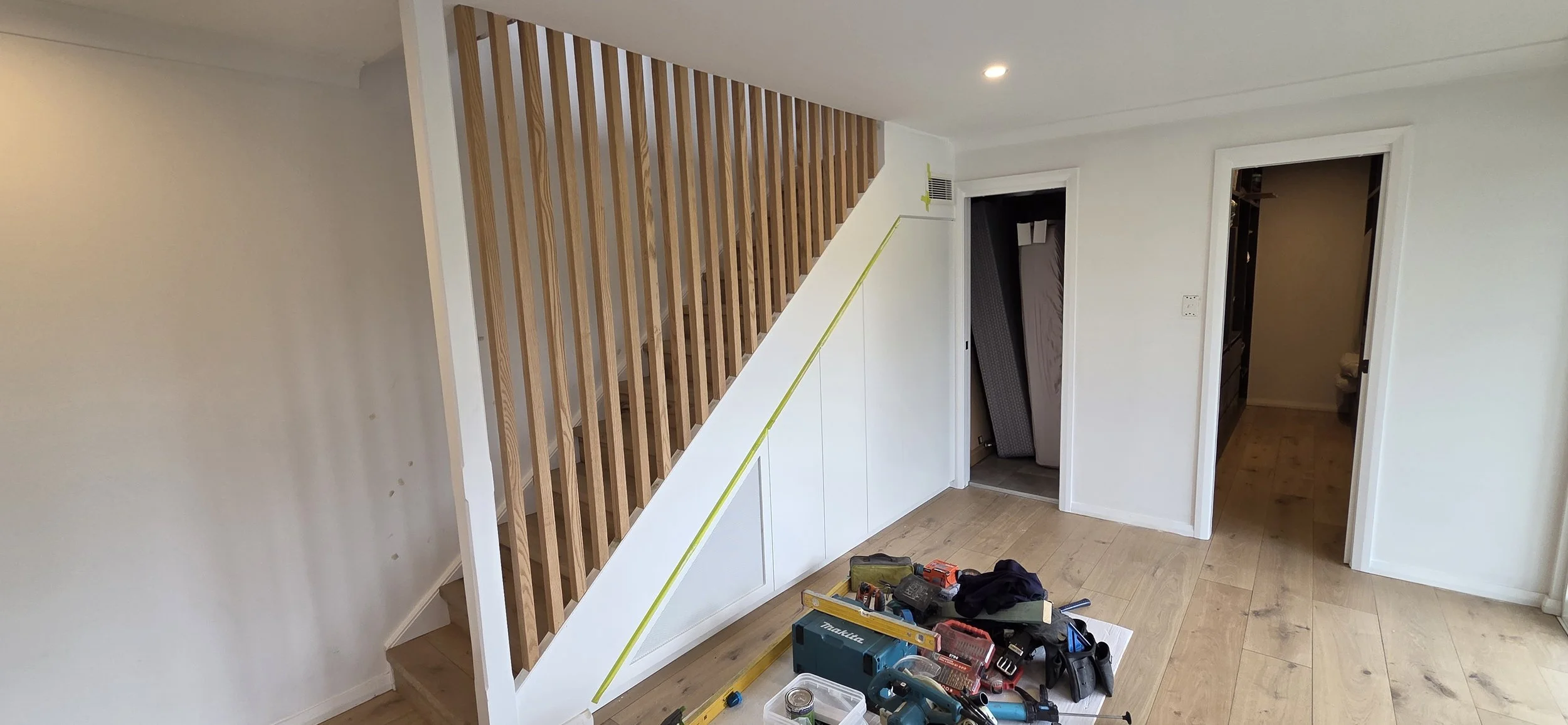Entry stair under construction, natural oak batten balustrade, with clever storage under