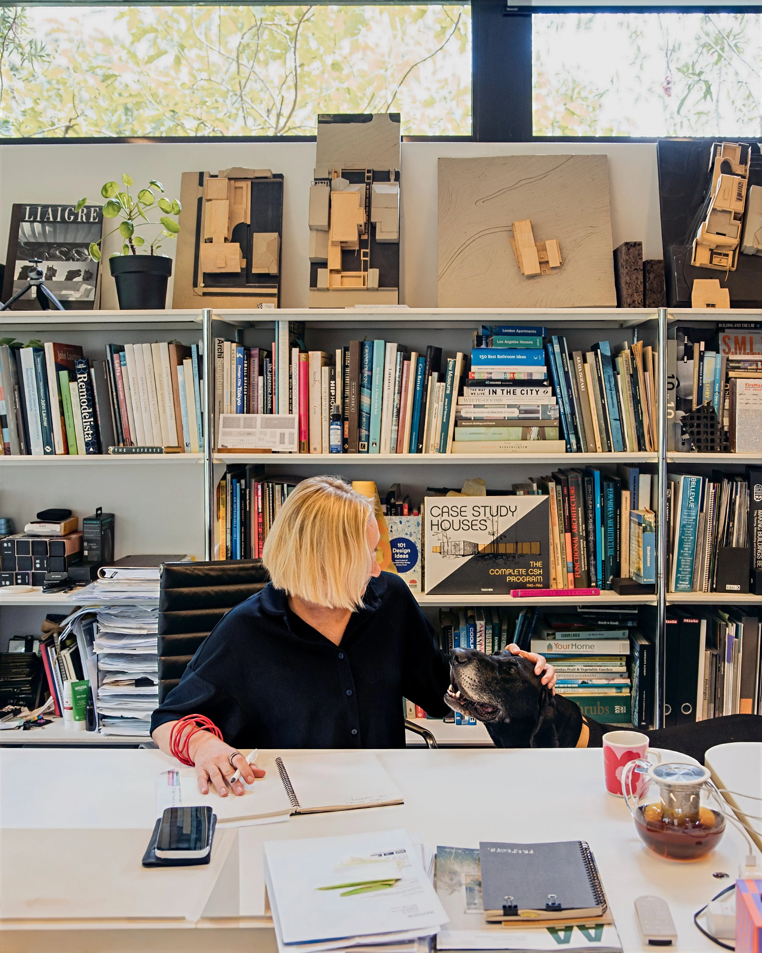 Female architect sitting at her desk surrounded by books, models and materials