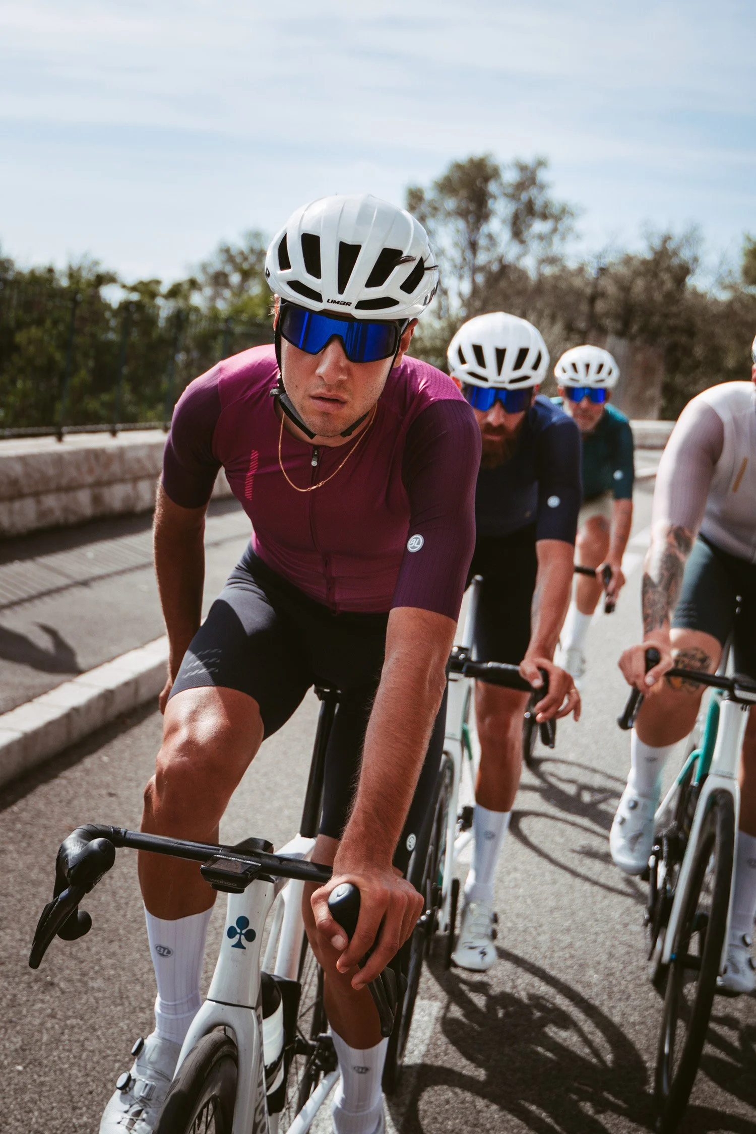 Group of cyclists riding on the road, wearing helmets and sunglasses.