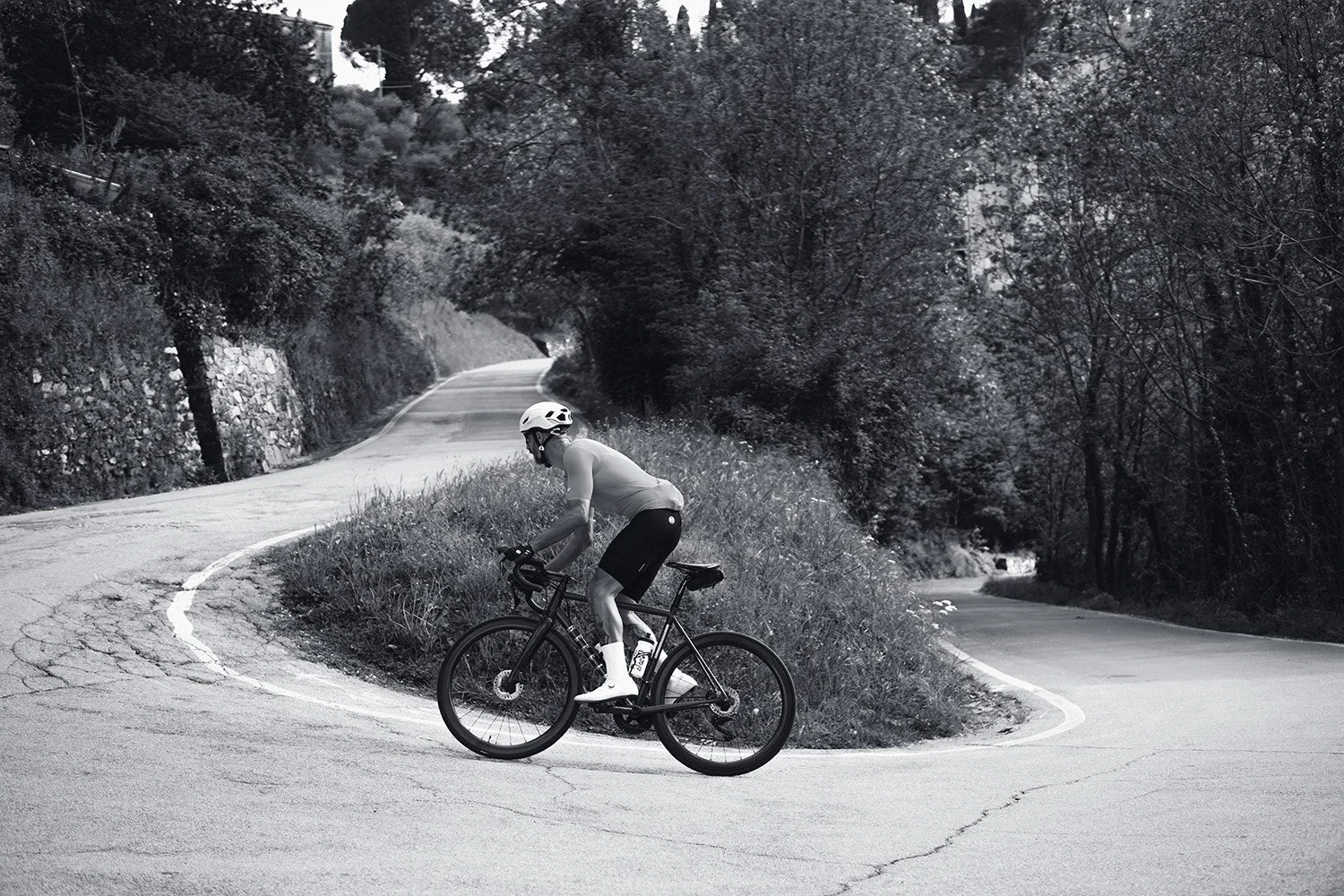 A person riding a bicycle on a winding mountain road surrounded by trees and natural scenery.
