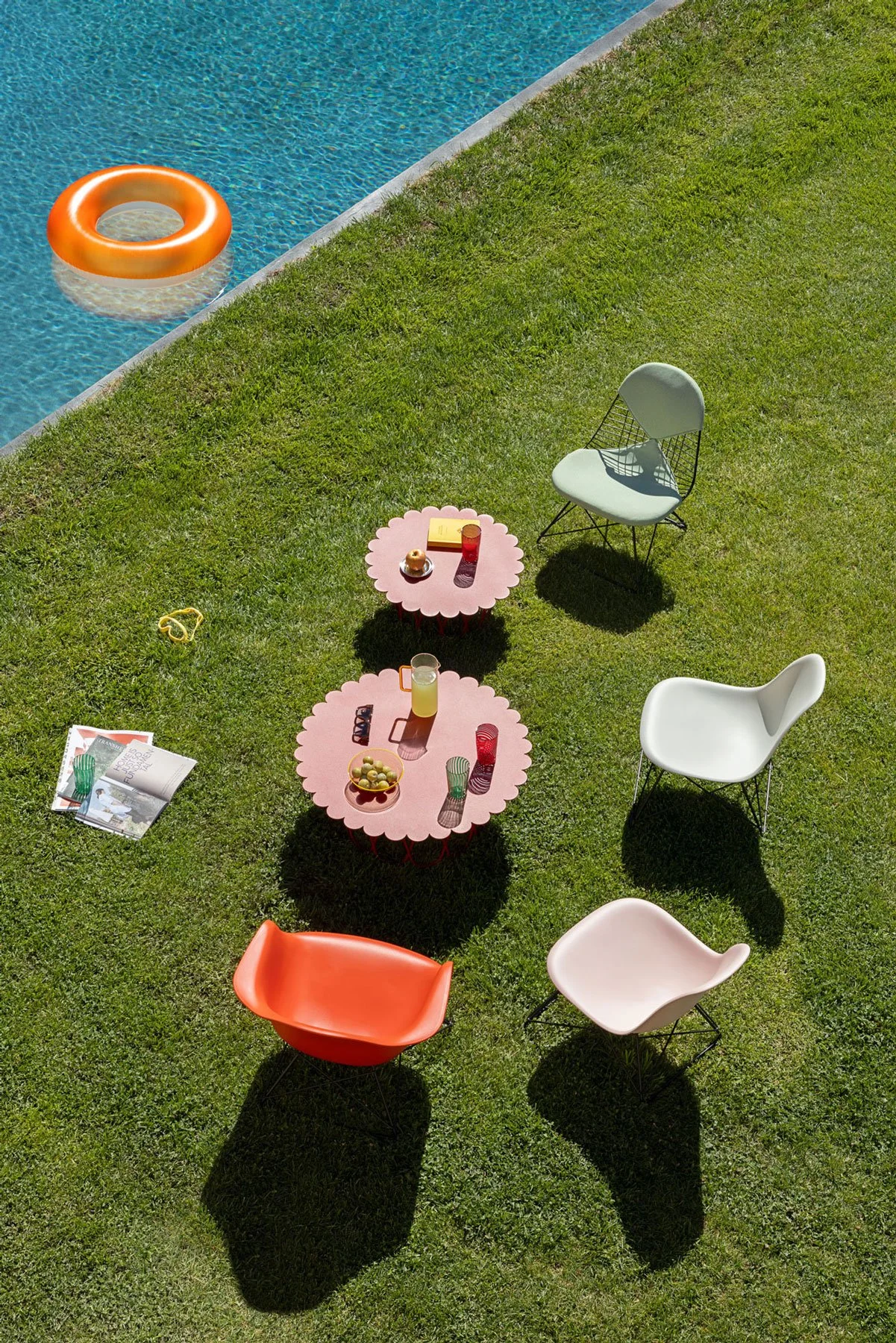 Outdoor Lounge in Wiese mit Eames Plastic- und Wire Chairs Lounge Sesseln. Pool ist im Hintergrund