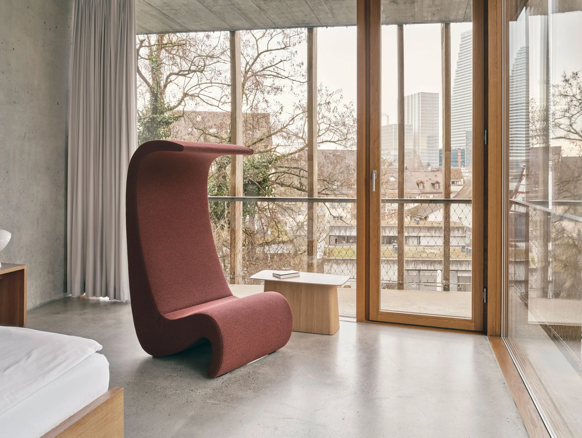 Jugendherberge Basel, Zimmer mit Amoebe Highback in der Farbe Kastanie. Bett daneben. Im Hintergrund sieht man die Rosch Türme von Basel.
