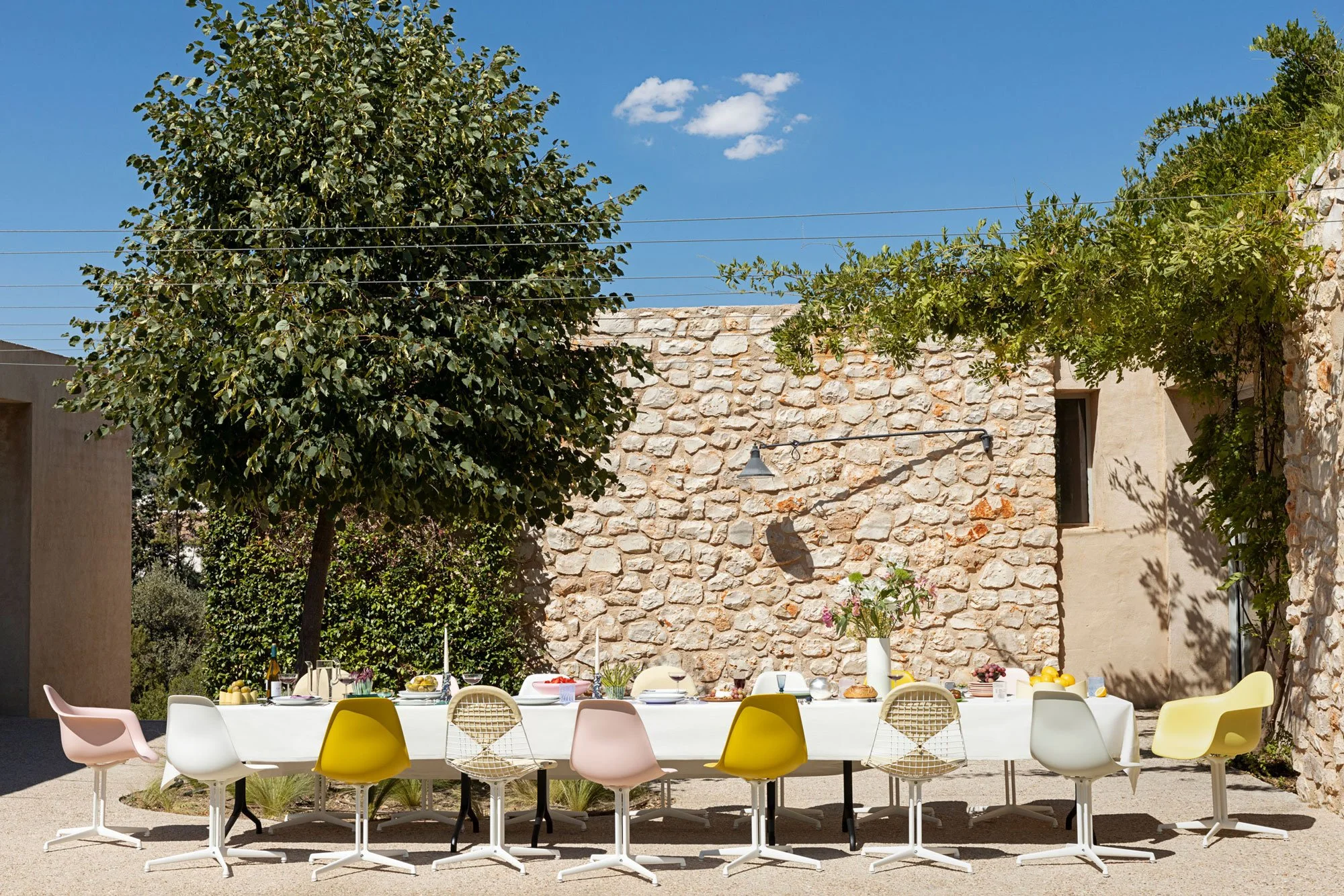 Outdoor Dining mit Eames Plastic- und Wire Chairs mit La Fonda Untergestell. Die Farben der Stühle sind gelb, rosa und weiss. 
