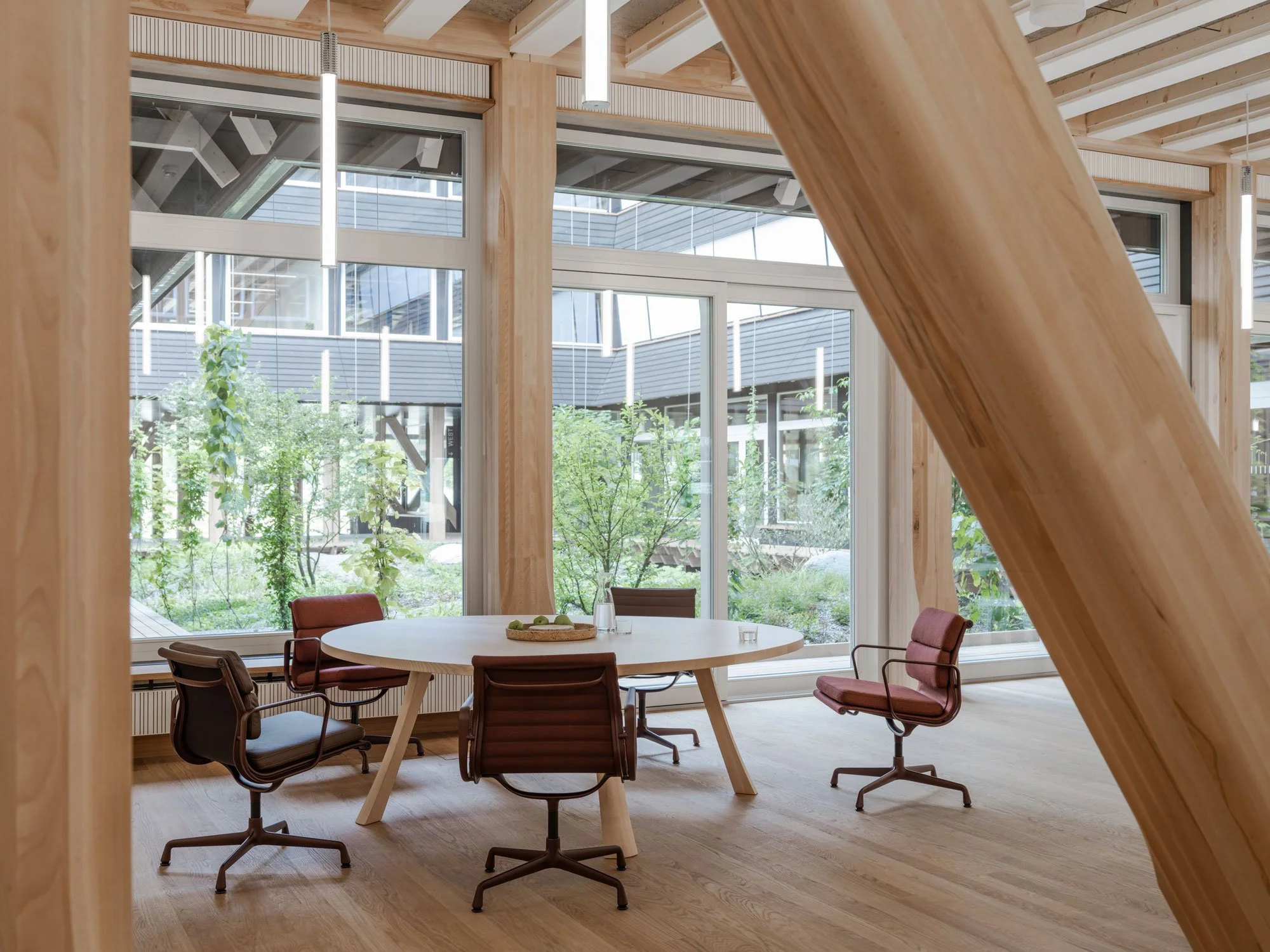 Im radikal nachhaltigen Büroneubau «Hortus» von Herzog & de Meuron werden die Updates des Alu Chairs fotografiert. Neue Alu Chairs an Tisch vor Fenster mit grünem Innenhof