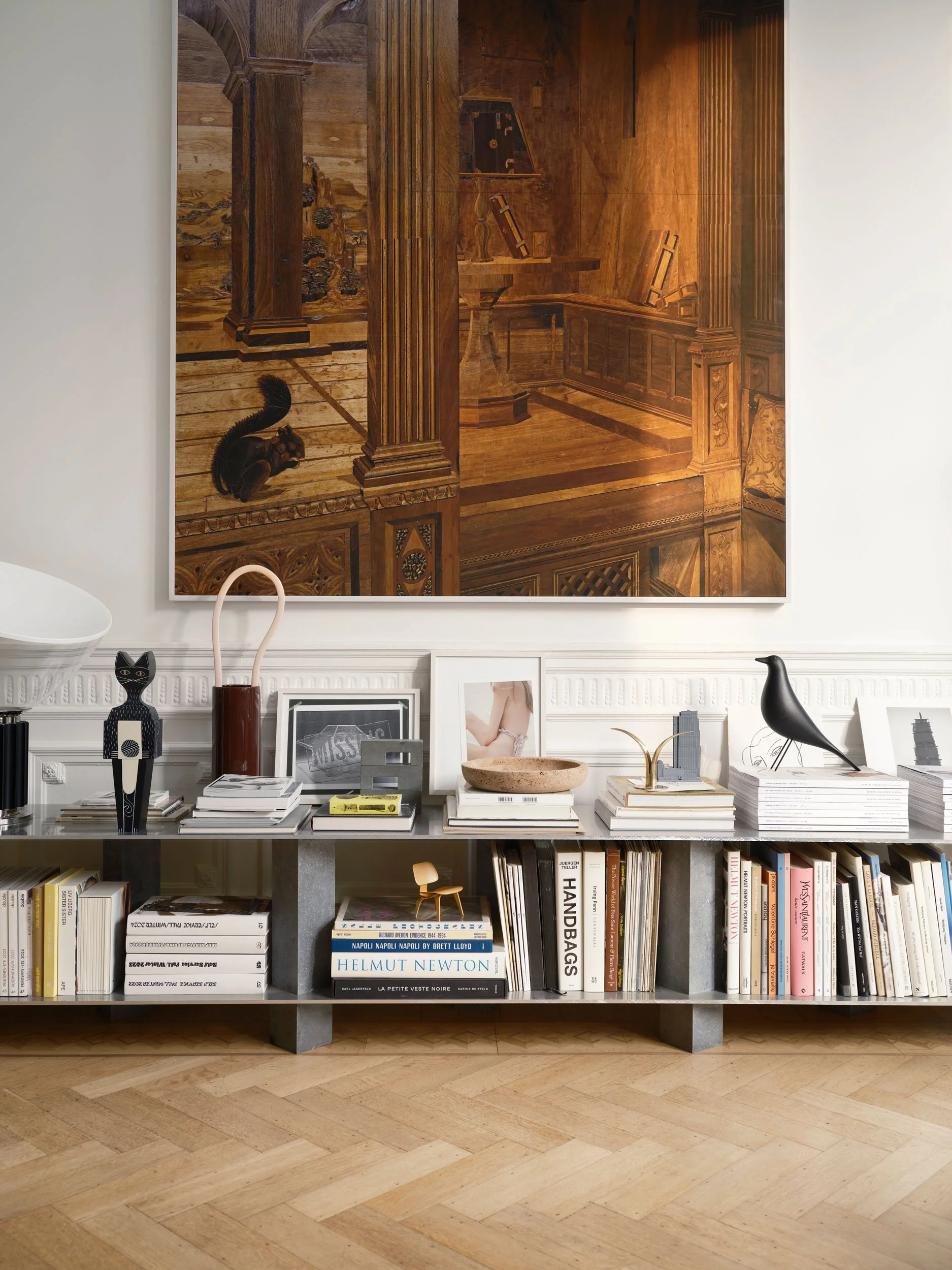 Home Stories for Winter 25 wurden beim Architekten David Van Severen und der Modefotografin Martina Bjorn fotografiert. Tiefes Bücherregal mit Eames House Bird, Bouroullec Vase und grosser Wooden Doll Cat. Grosser Bild an Wand mit kleinem Eichhörnche