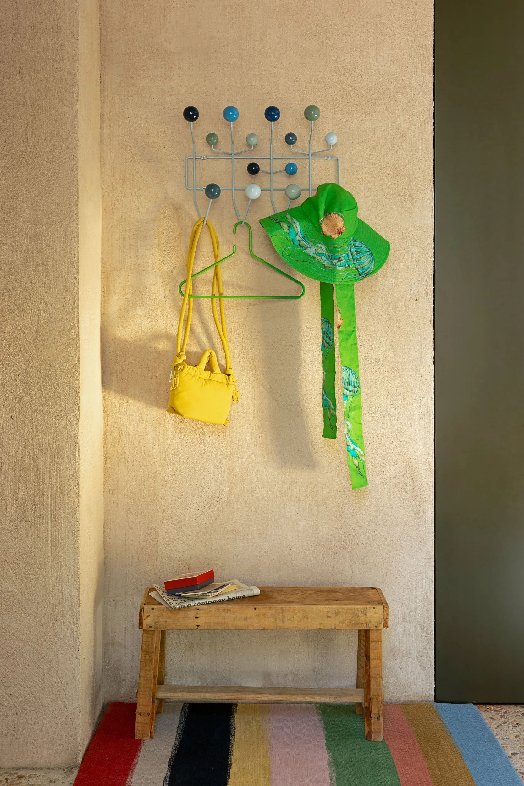 Hang it all in blau mit Hut und Tasche. Sitzbank darunter und farbiger Teppich