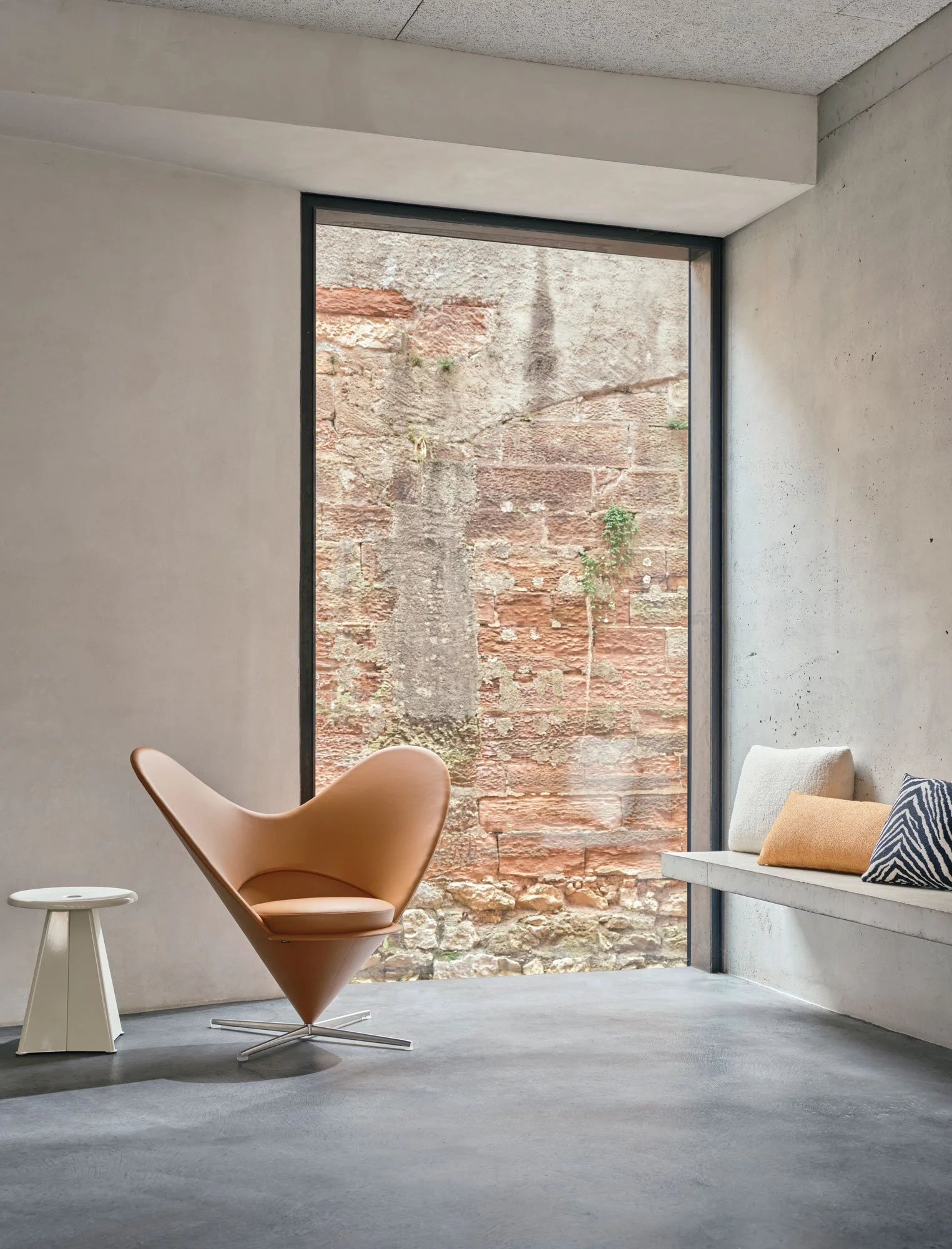 Jugendherberge Basel, Heart Cone Chair in Leder vor Fenster mit weissem Tabouret métallique von Jean Prouvé. Sitzbereich mit Kissen