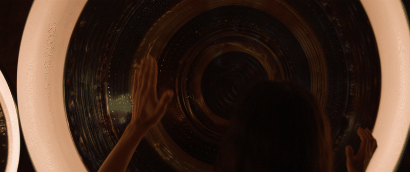 Woman with long dark hair testing sound waves and effects with hand movements over gong.