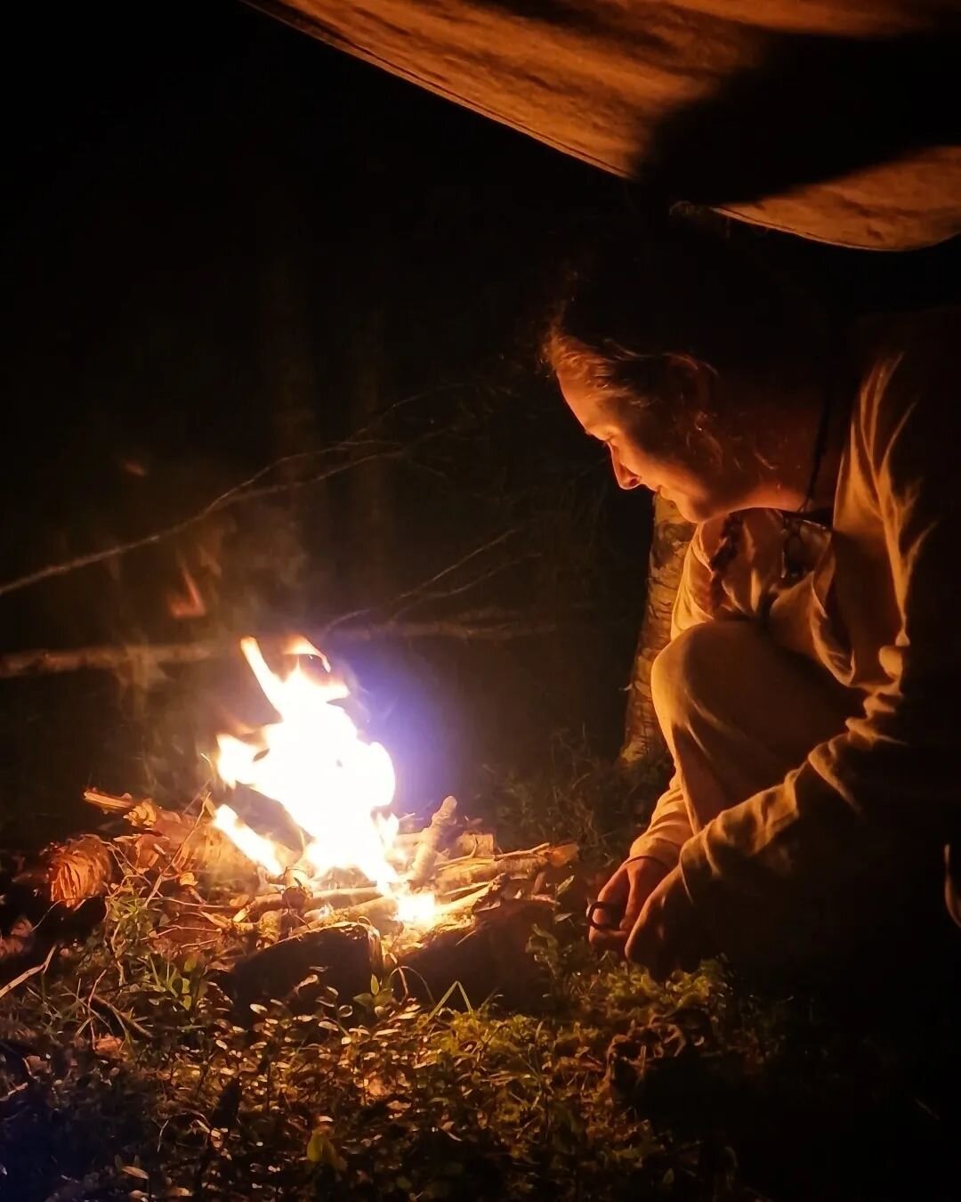 Darkness forms a wall around the camp. The first raindrops have started to fall. We got the tarp up at the last minute. Now we'll manage to stay dry tonight. The sound of the wind in the trees and the crackling of the bonfire fills the air. The tarp 