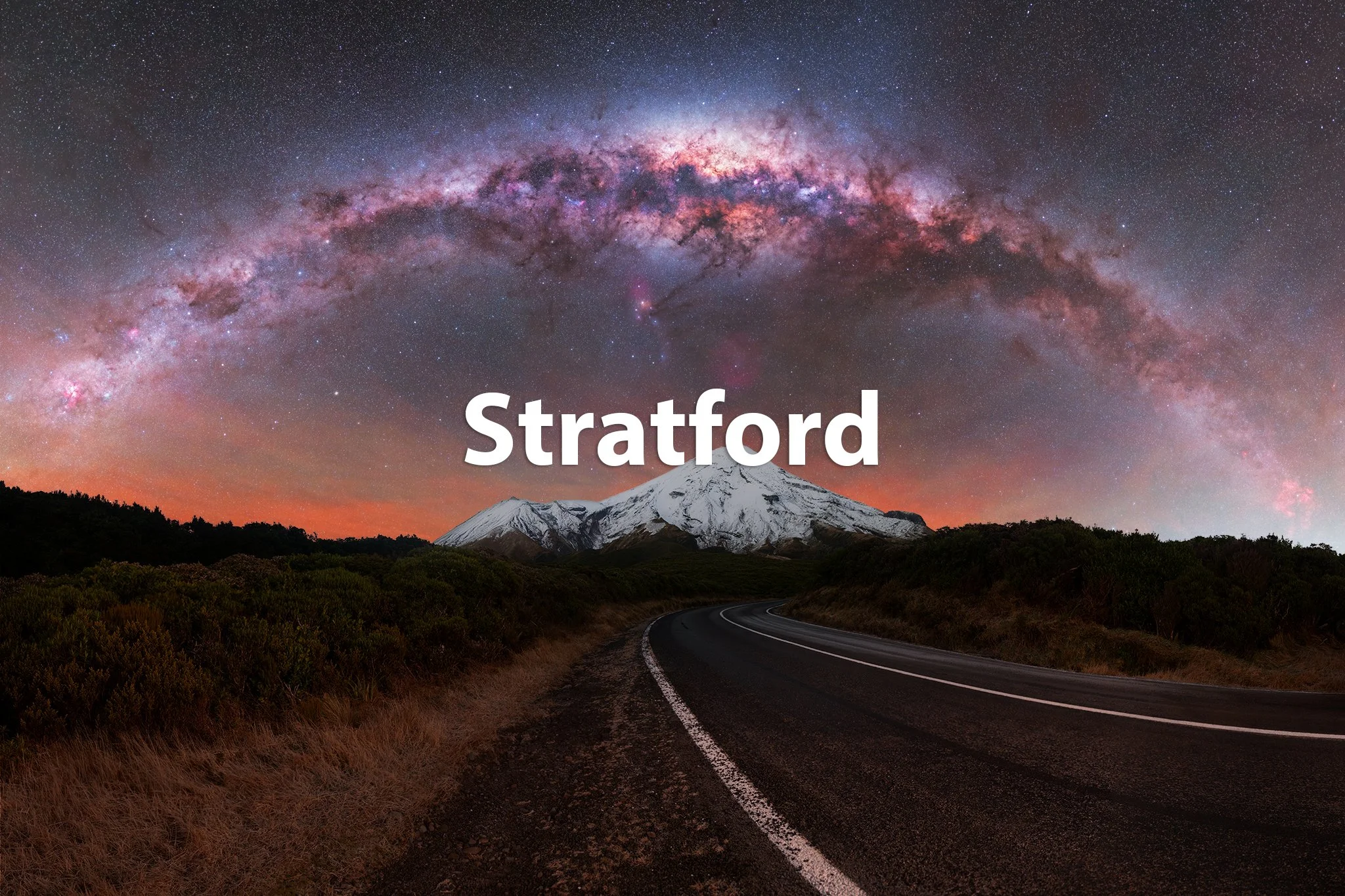 A mountainous landscape featuring a snow-capped peak, a winding road, a forested foreground, and a starry night sky with the Milky Way galaxy arching overhead; the word "Stratford" is superimposed in white text.