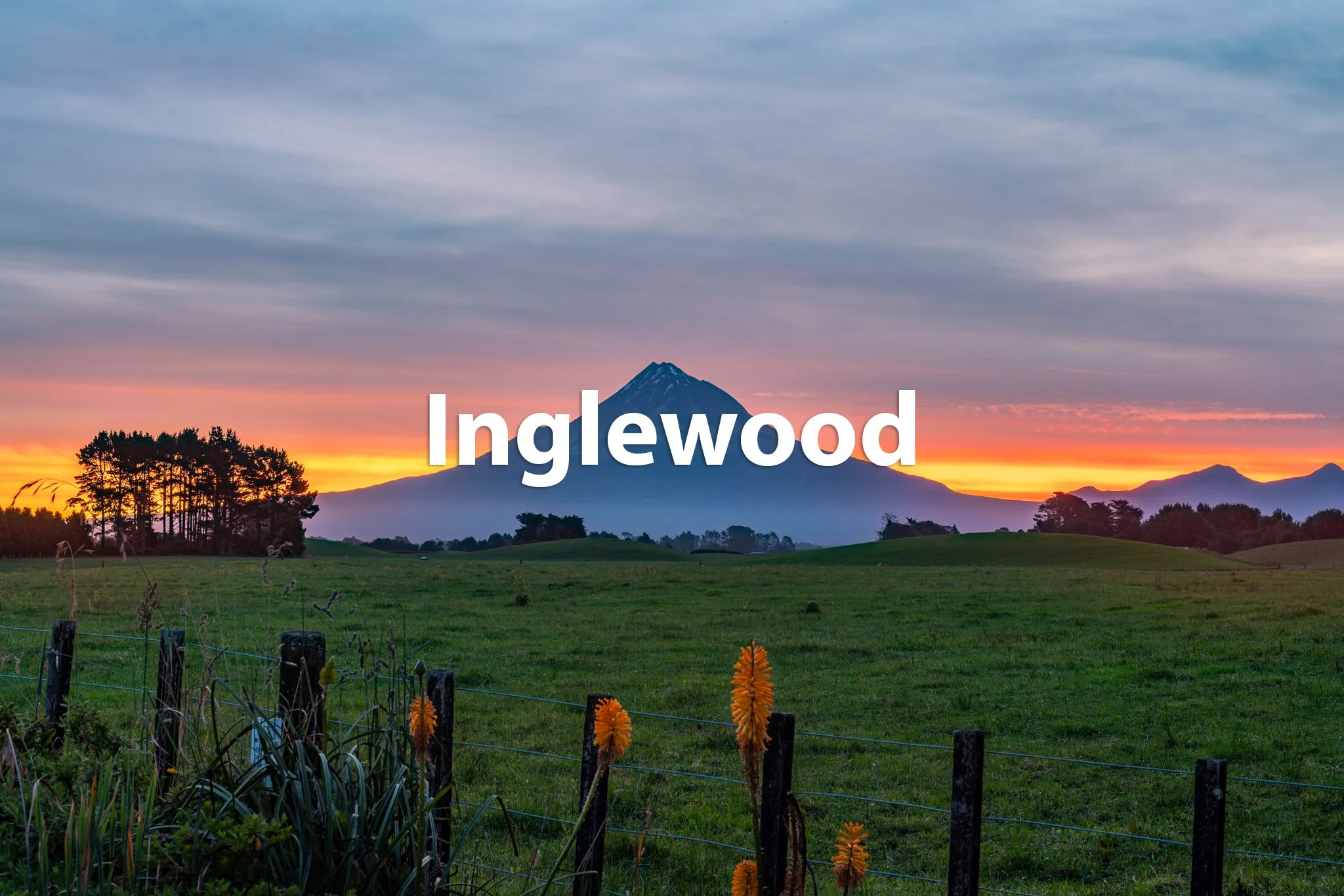 A scenic landscape with green fields, a fence with yellow flowers, trees, and a mountain in the background at sunset, with the word 'Inglewood' overlaid.