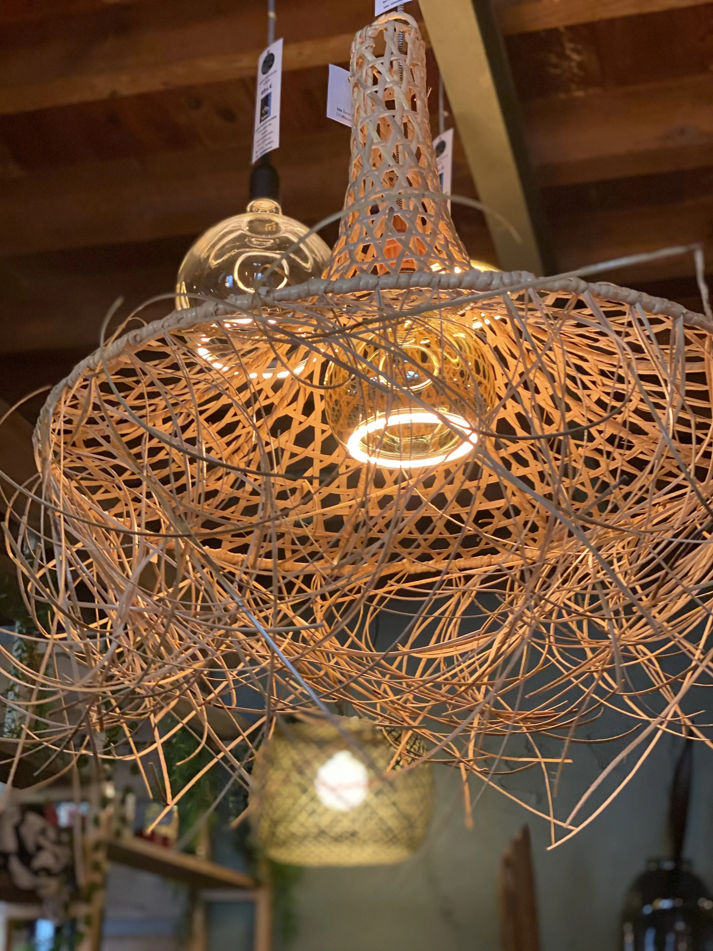 Suspension lumineuse en osier, design artisanal, avec ampoules allumées dans un intérieur boisé.