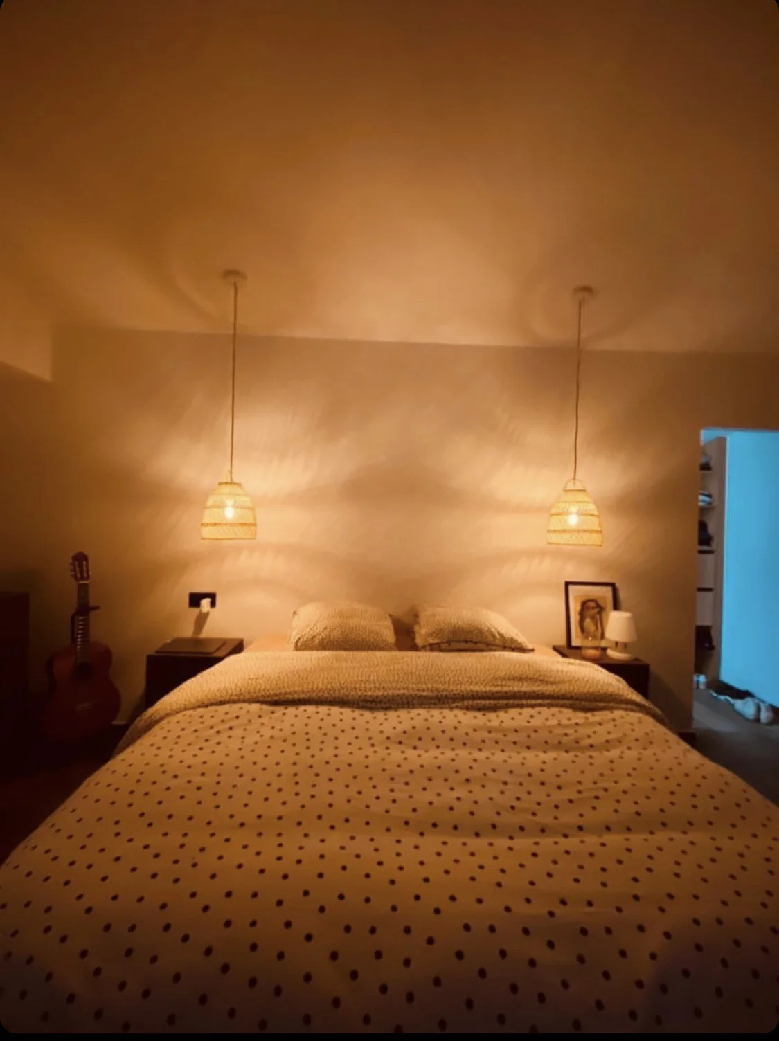 Chambre à coucher avec un lit double, des suspensions lumineuses, une guitare et des tables de nuit.